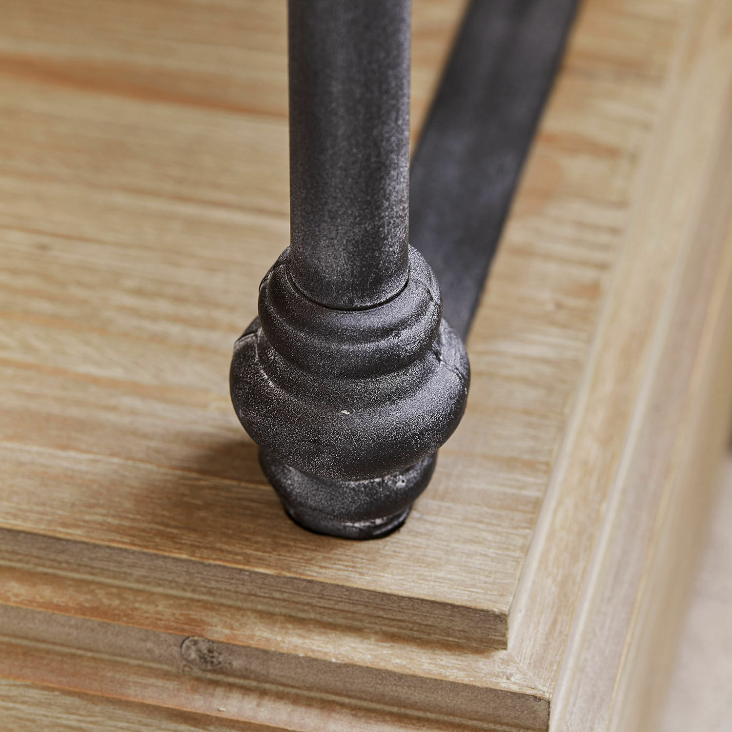 Schwarzes Metallmöbelfuß auf hellem Holzbrett, Detail der Möbelkonstruktion