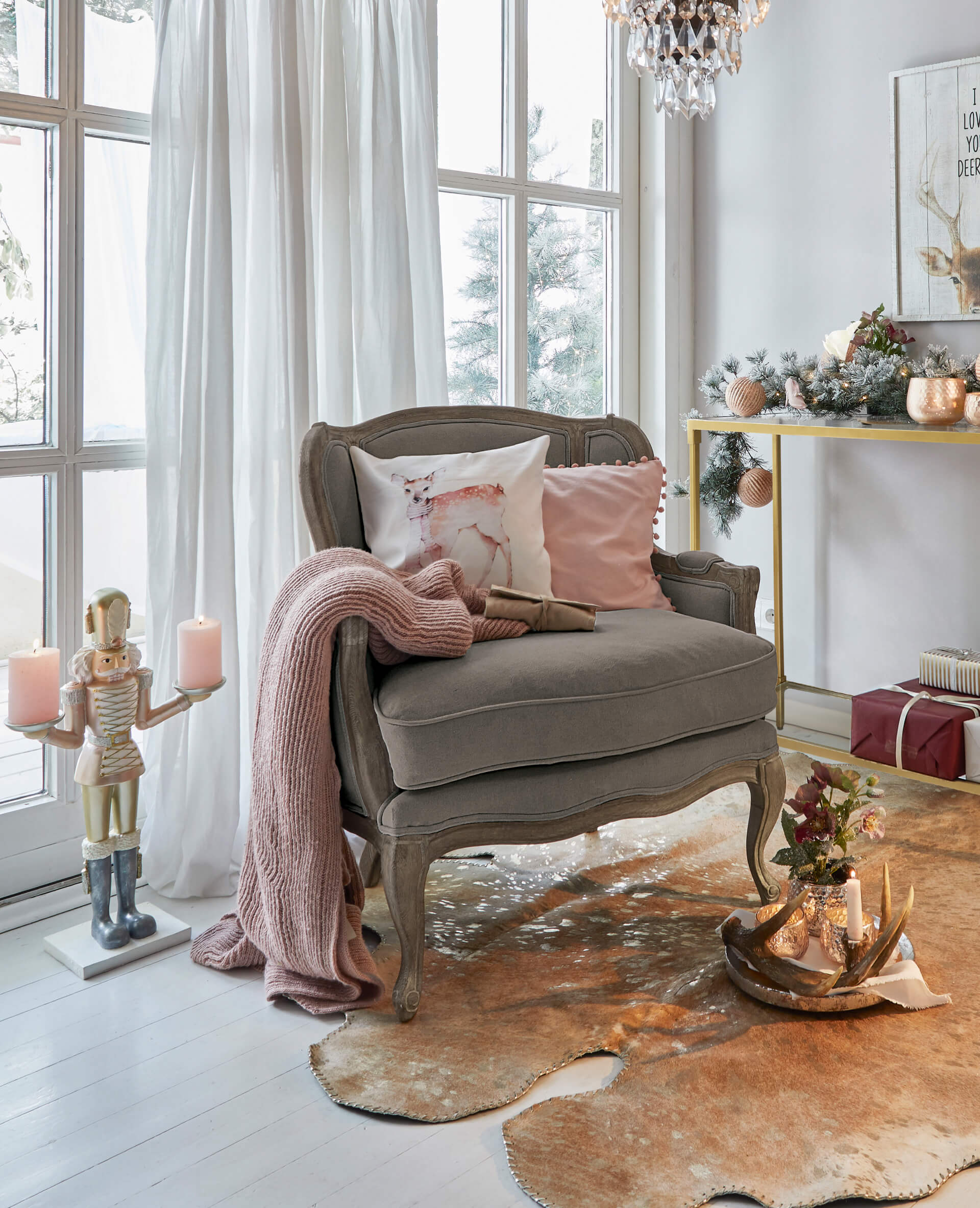 Grau gepolsterte Couch mit rosa Decke und Kissen in gemütlichem Wohnzimmer mit Weihnachtsdeko