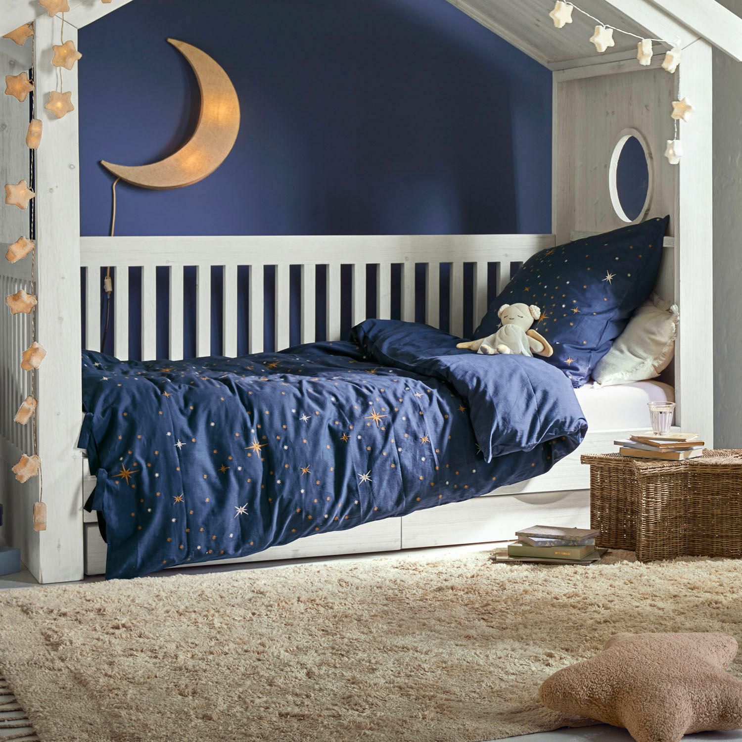 Bettwäsche Starwhisper Weißes Kinderbett aus Holz mit dunkelblauer Sternenbettwäsche und Mondlampe im gemütlichen Kinderzimmer