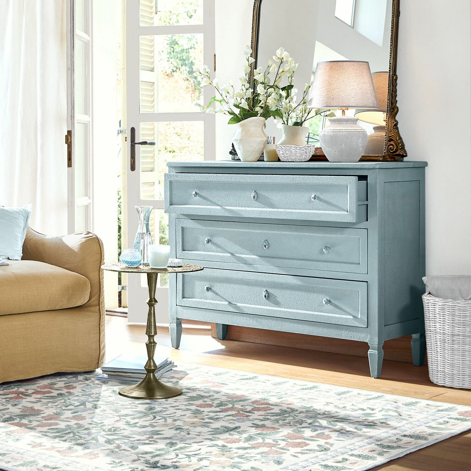 Blaue Holzkommode mit drei Schubladen in hellem Wohnzimmer mit Dekoration und Lampe