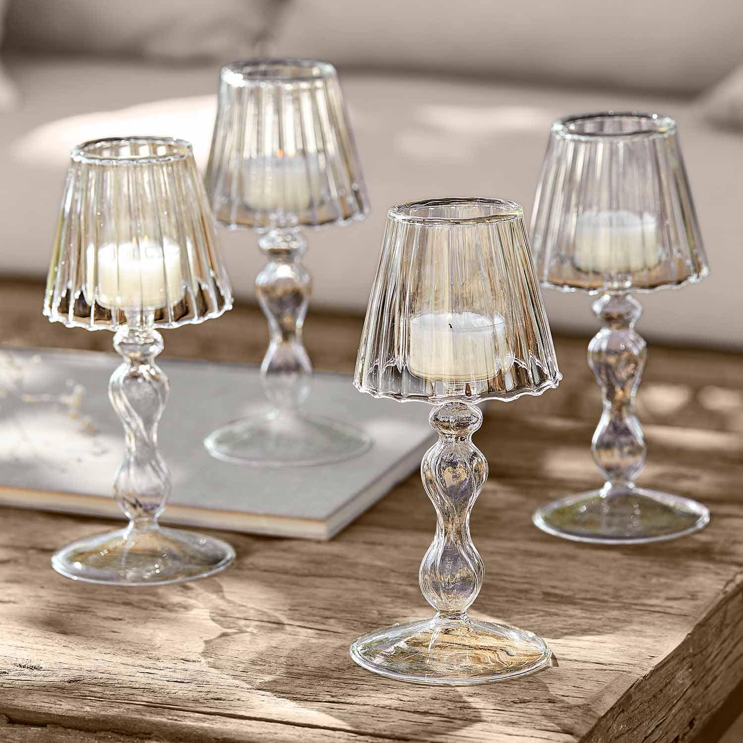 Transparente Glas-Kerzenhalter mit weißen Kerzen auf Holztisch als Wohnaccessoire