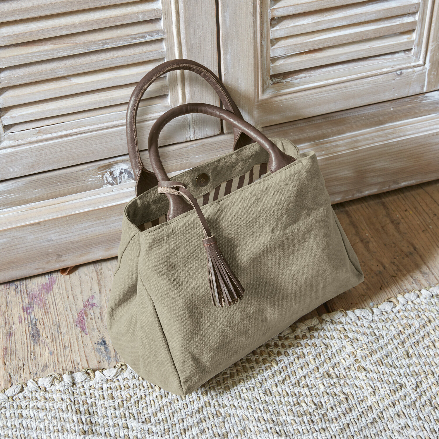 Tasche Hoya Beige Stofftasche mit braunen Ledergriffen und Quaste auf Holzboden