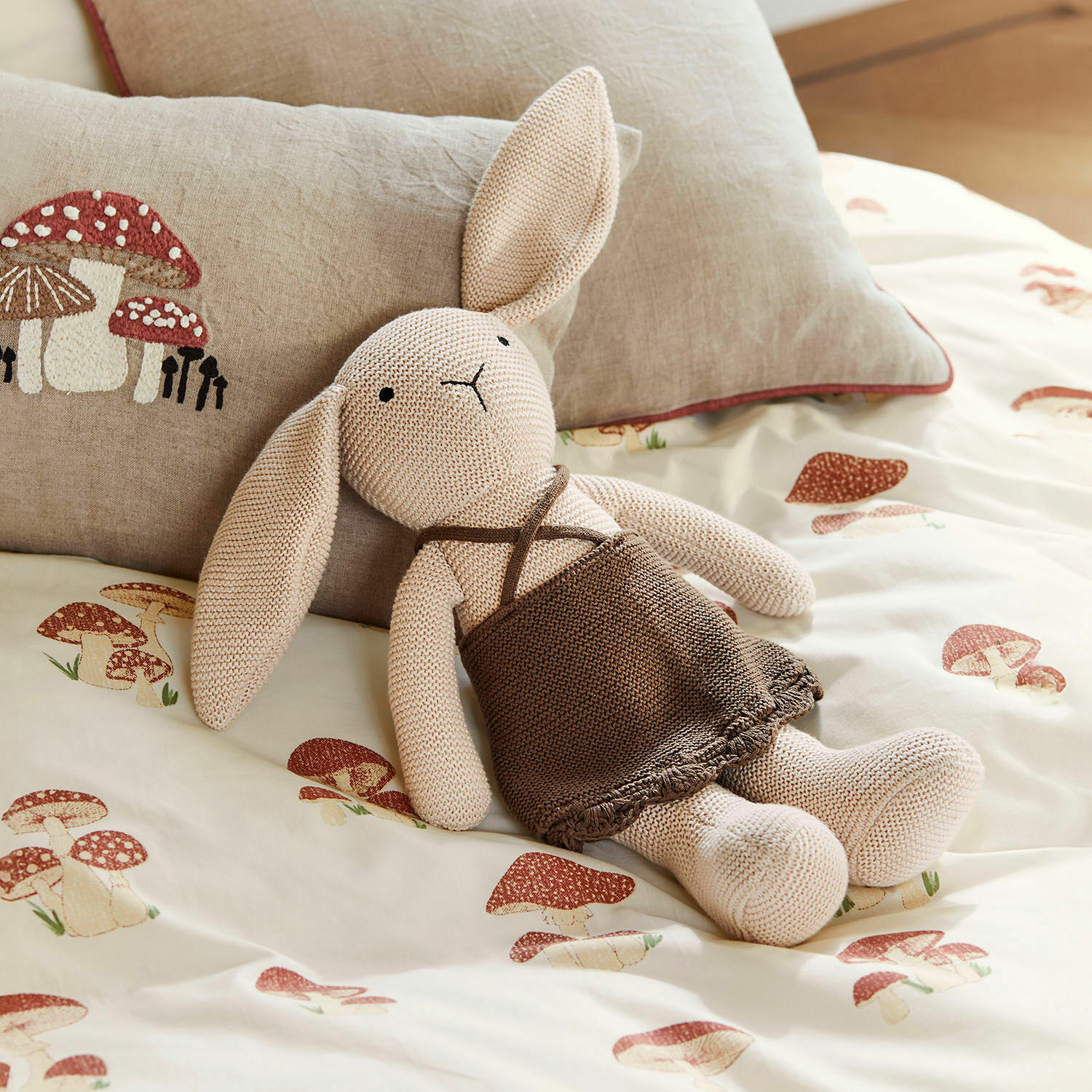 Stofftier Flicka Beiger gestrickter Hase mit braunem Kleid auf Bettwäsche mit Pilzmotiv, dekoratives Pilzkissen