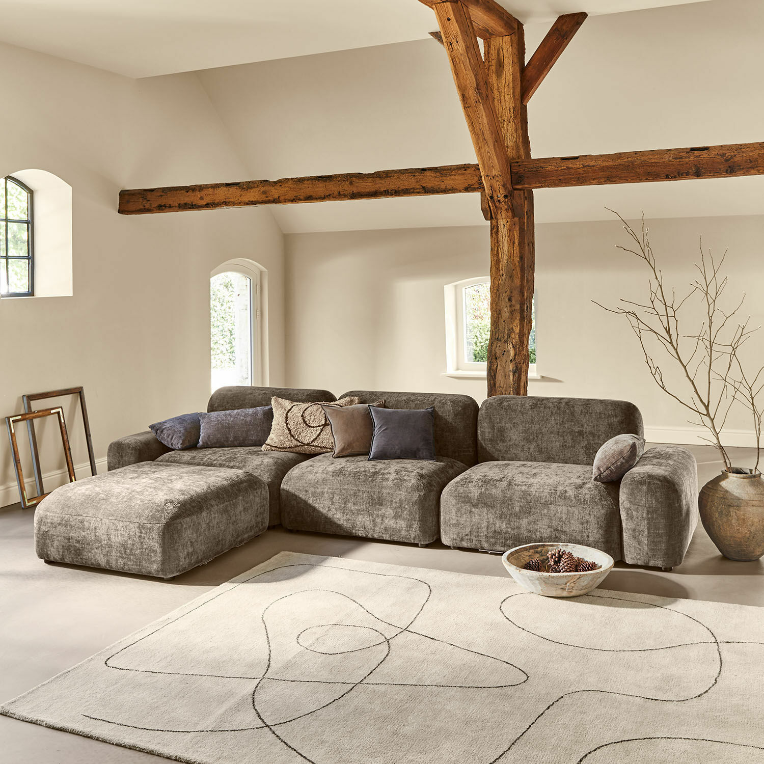 Sofa Marnivelle Graues modular aufgebautes Sofa aus Stoff in modernem Wohnzimmer mit Holzbalken und hellem Teppich