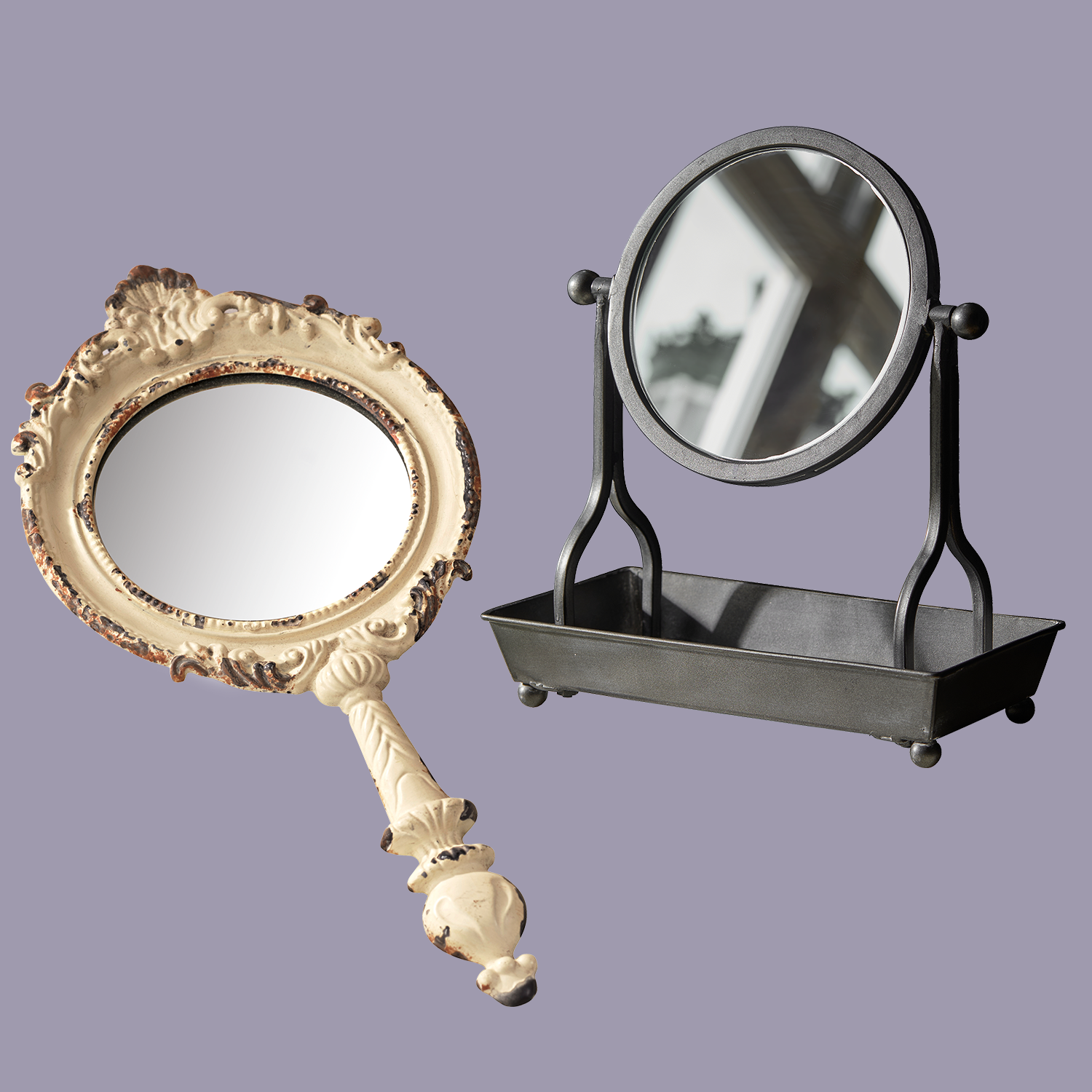 Zwei dekorative Spiegel, ein Handspiegel mit cremefarbenem Rahmen, ein Standspiegel mit schwarzem Metallrahmen