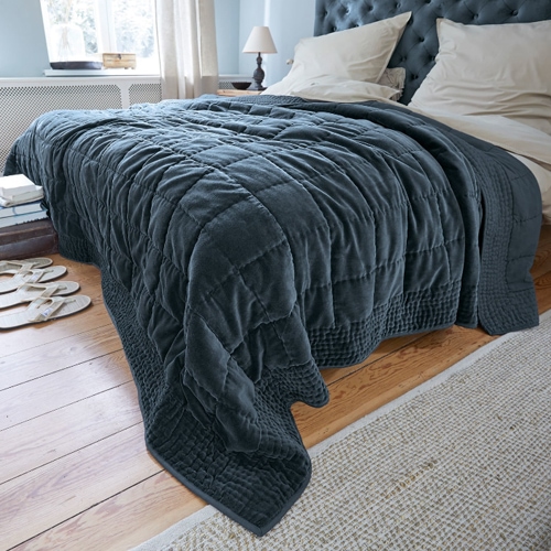 Dunkelgraue gesteppte Decke aus weichem Material auf Bett in hellem Schlafzimmer, Wohntextil