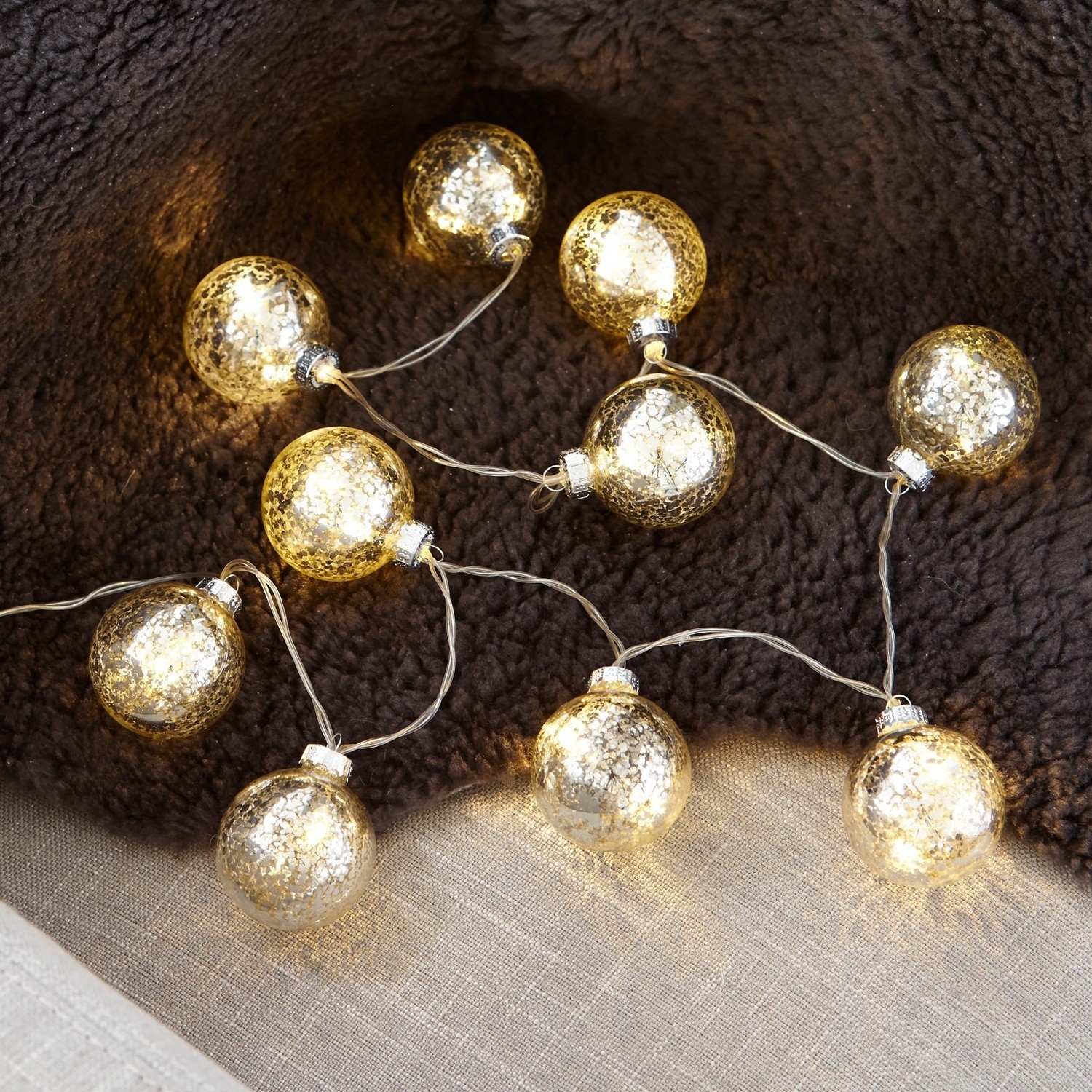 Dekorative Lichterkette aus transparentem Glas in Kugelform mit warmem Licht auf dunklem Hintergrund