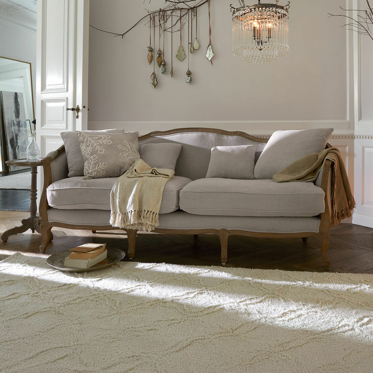 Sofa Monneville Graues Sofa mit Holzrahmen und weichen Kissen in klassischem Wohnzimmer mit Teppich und Lampe