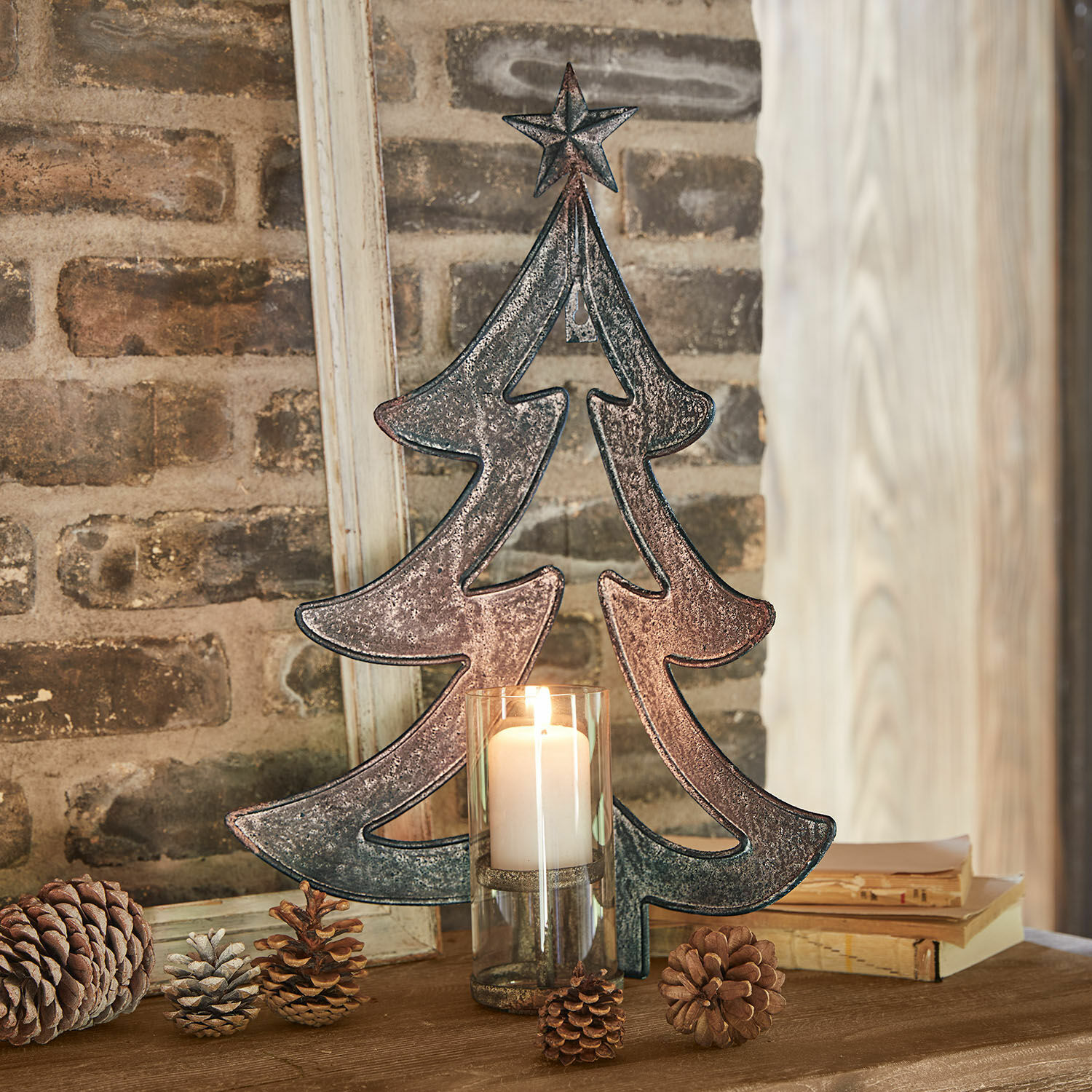 Wandkerzenhalter Jolise Metall-Weihnachtsbaum-Dekoration mit Stern und Kerze im Glas auf Holztisch mit Kiefernzapfen