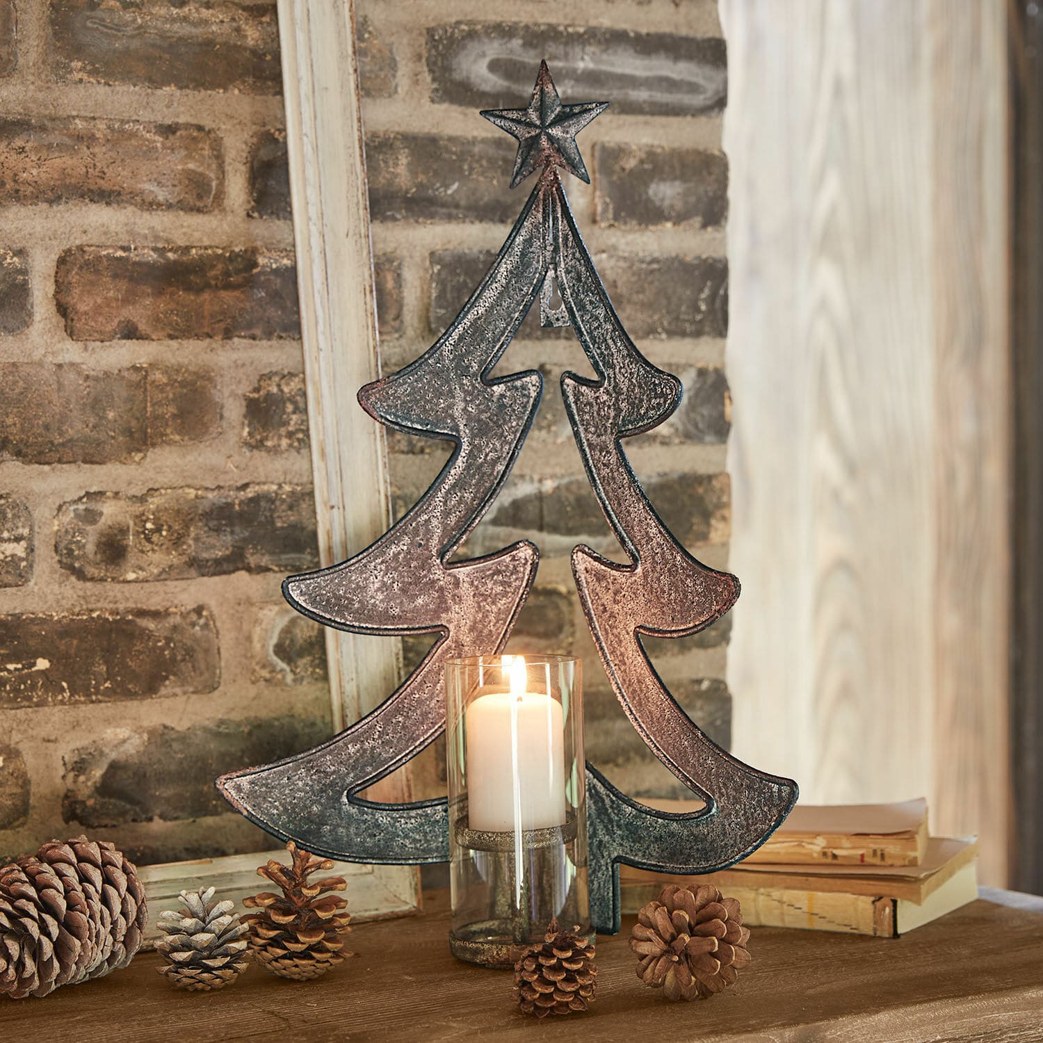 Wandkerzenhalter Jolise Metall-Weihnachtsbaum-Dekoration mit Stern und Kerze im Glas auf Holztisch mit Kiefernzapfen