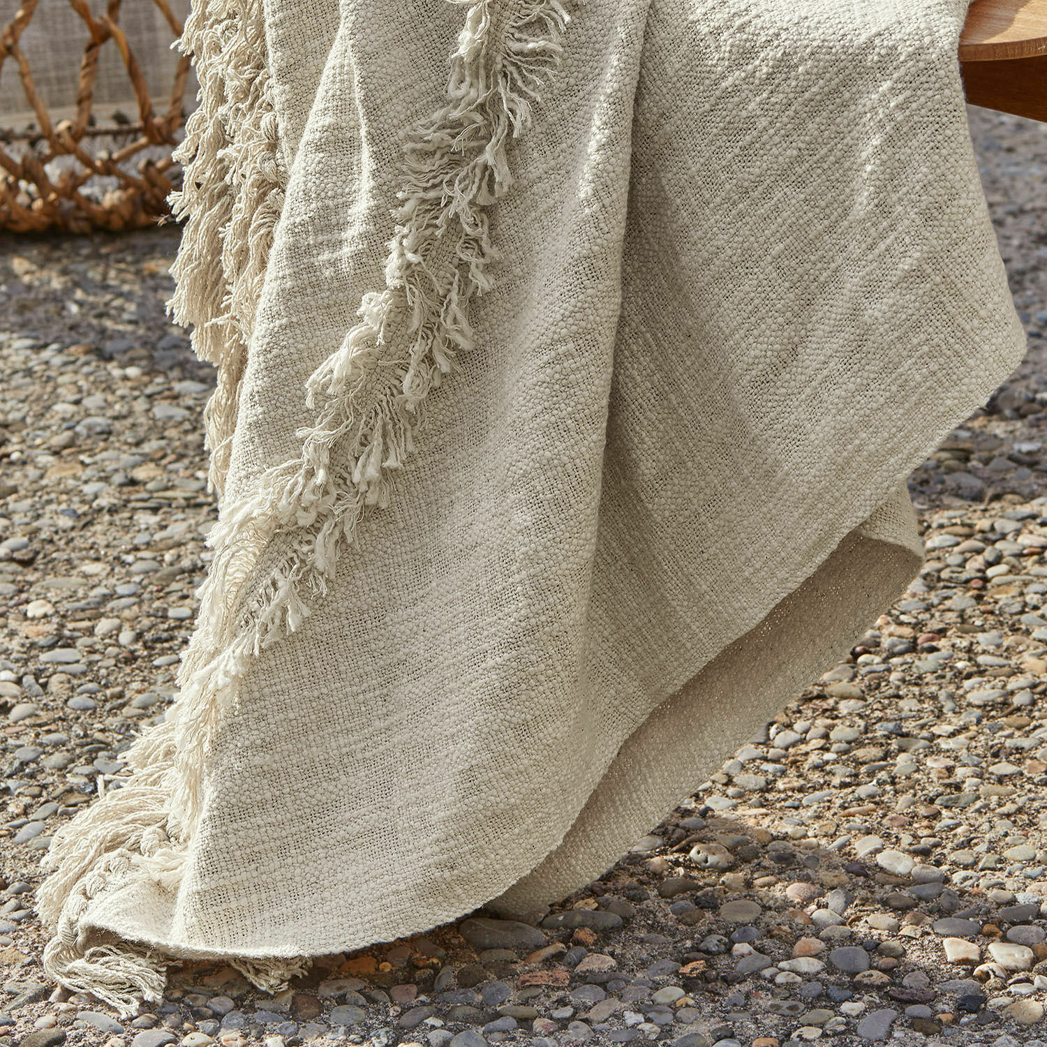 Beige Decke mit Fransen aus weichem Stoff auf Kiesboden, Wohn- und Gartendekoration