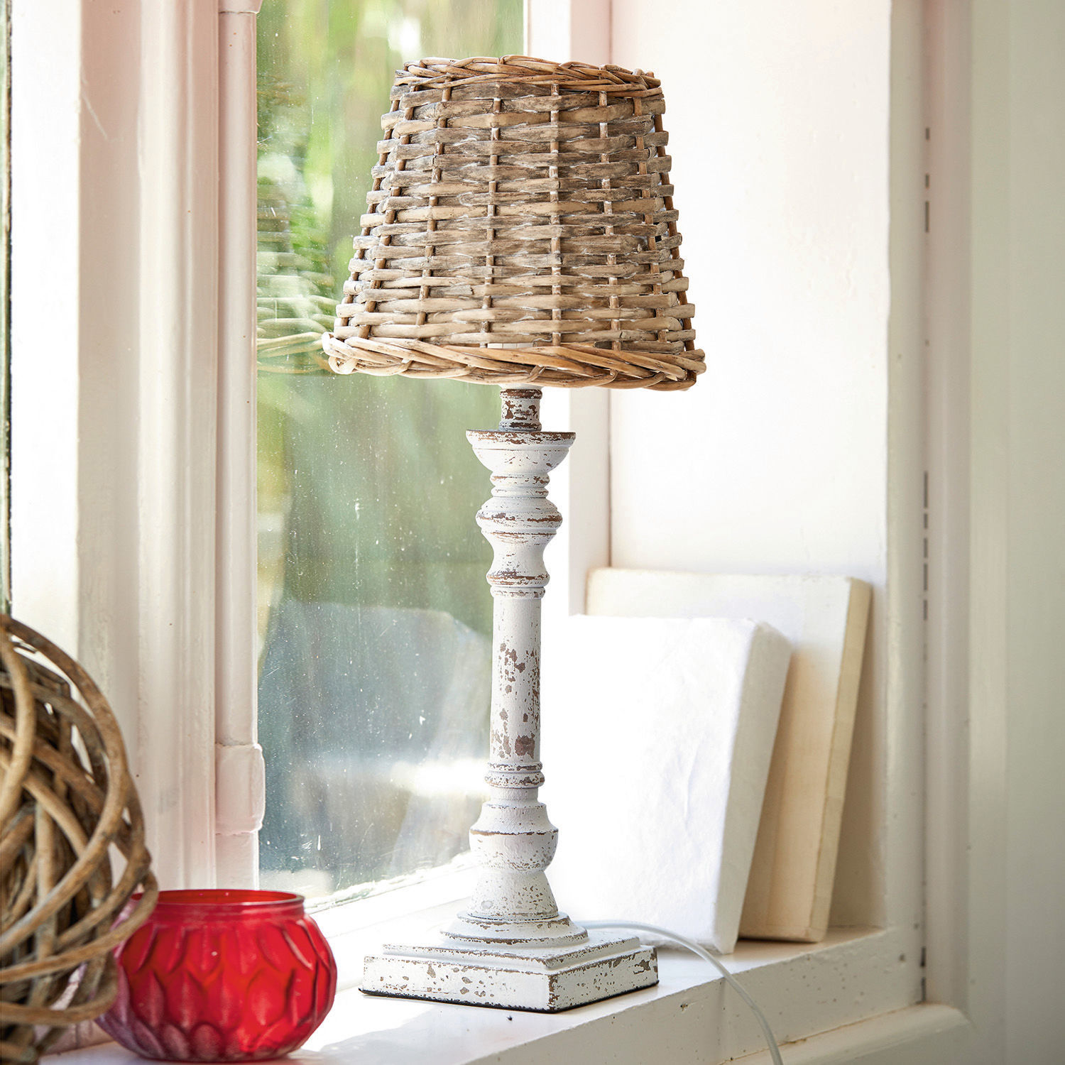 Tischlampe Noelie Tischlampe aus weißem, antik wirkendem Metall mit natürlichem Korbgeflecht-Schirm am Fenster