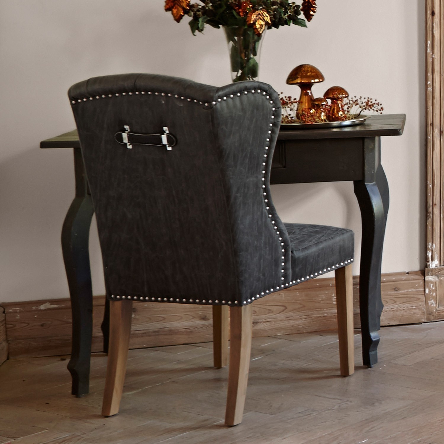 Schwarzer Stuhl aus Kunstleder mit Holzbeinen an dunklem Holztisch im Vintage-Stil