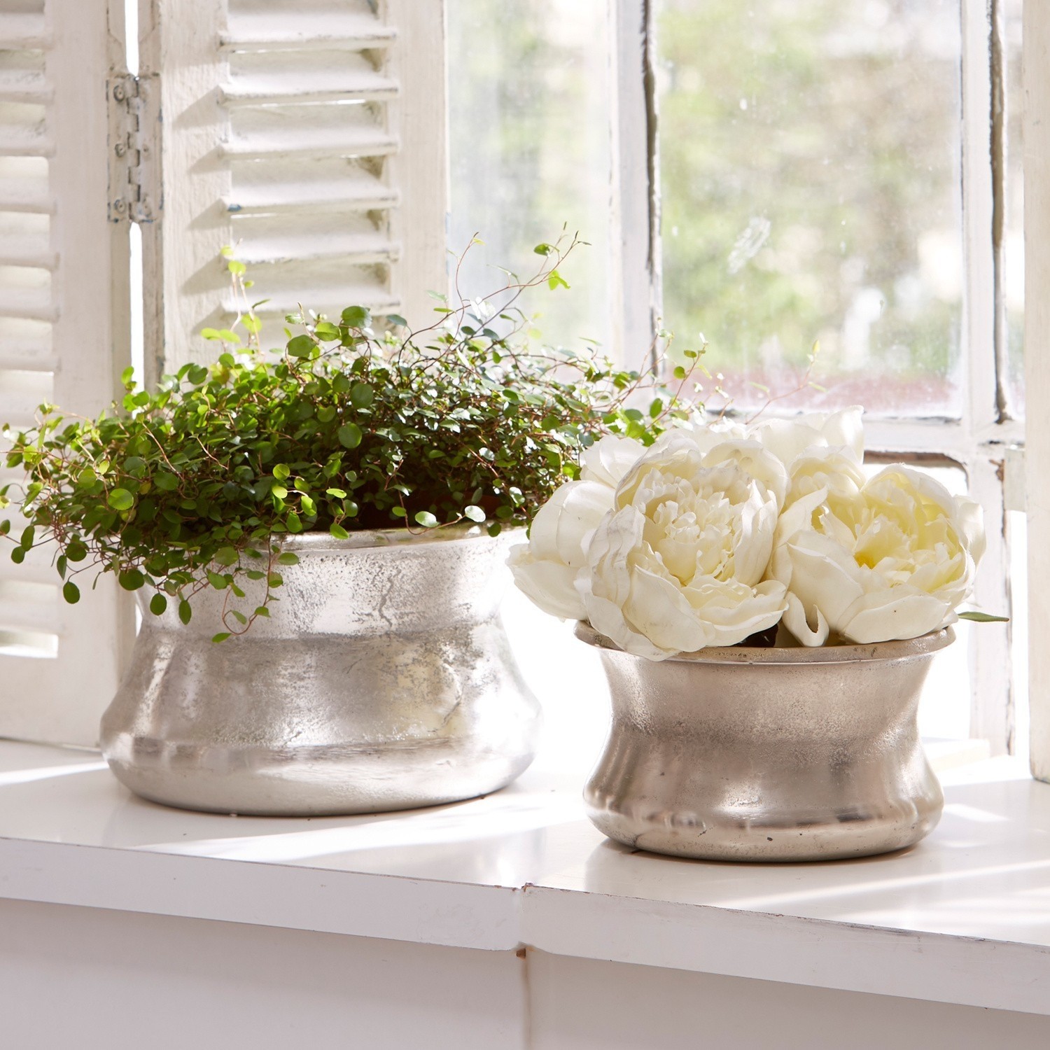 Vase 2er Set Riona Zwei silberne Metallblumentöpfe auf Fensterbank mit grüner Pflanze und weißen Dekoblumen