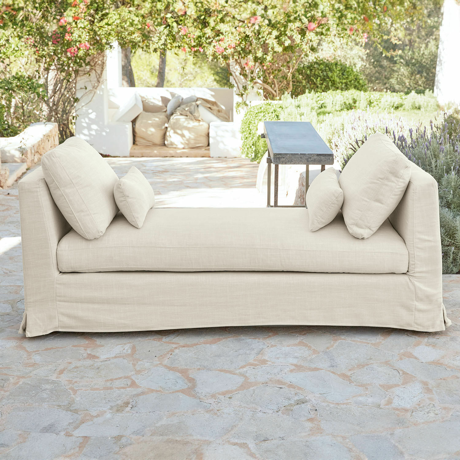 Beige Sofa aus Stoff mit Kissen auf Stein-Terrasse, komfortable Gartenmöbel im Außenbereich