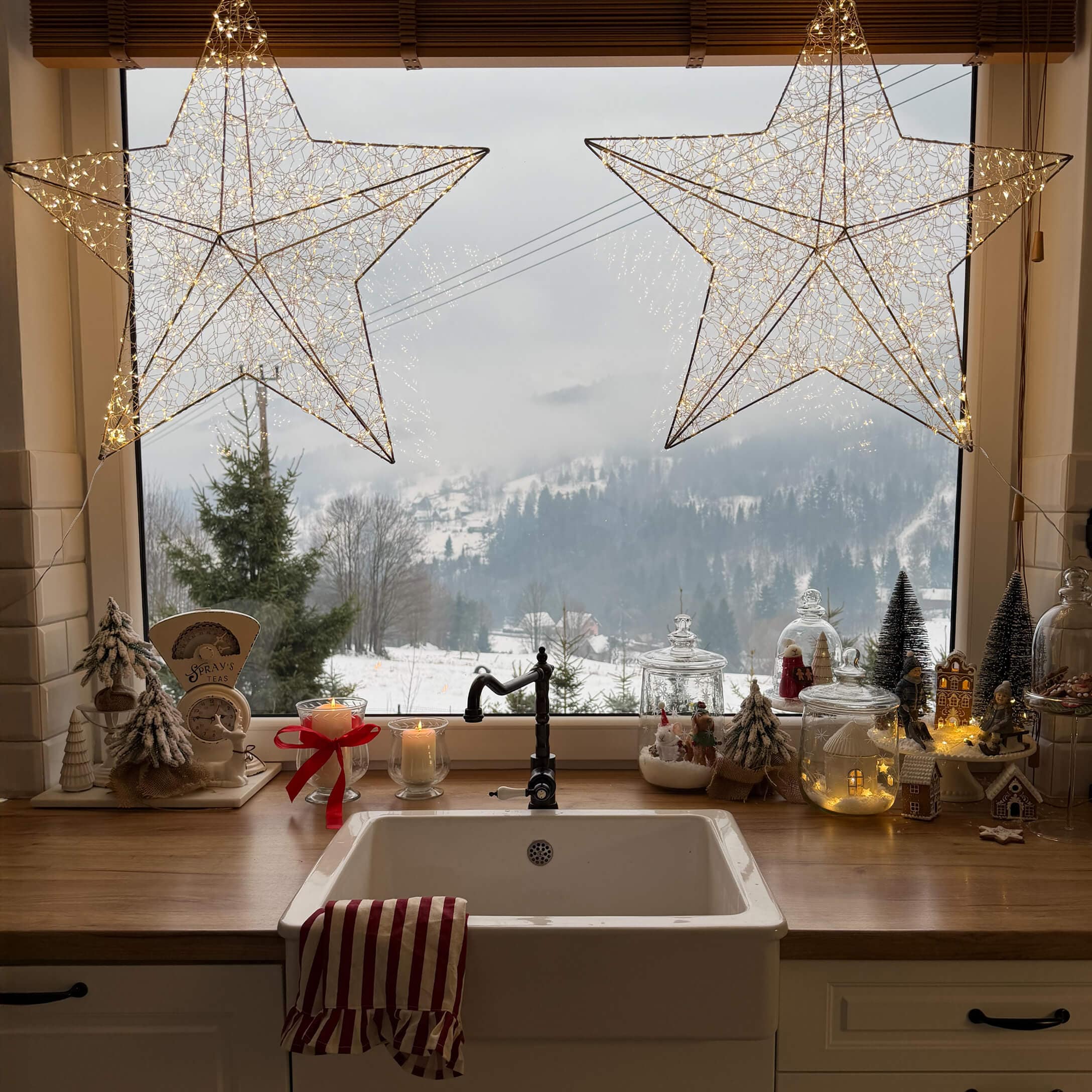 Küche mit weißem Spülbecken, Holzarbeitsplatte, Weihnachtsdekorationen und winterlicher Landschaft