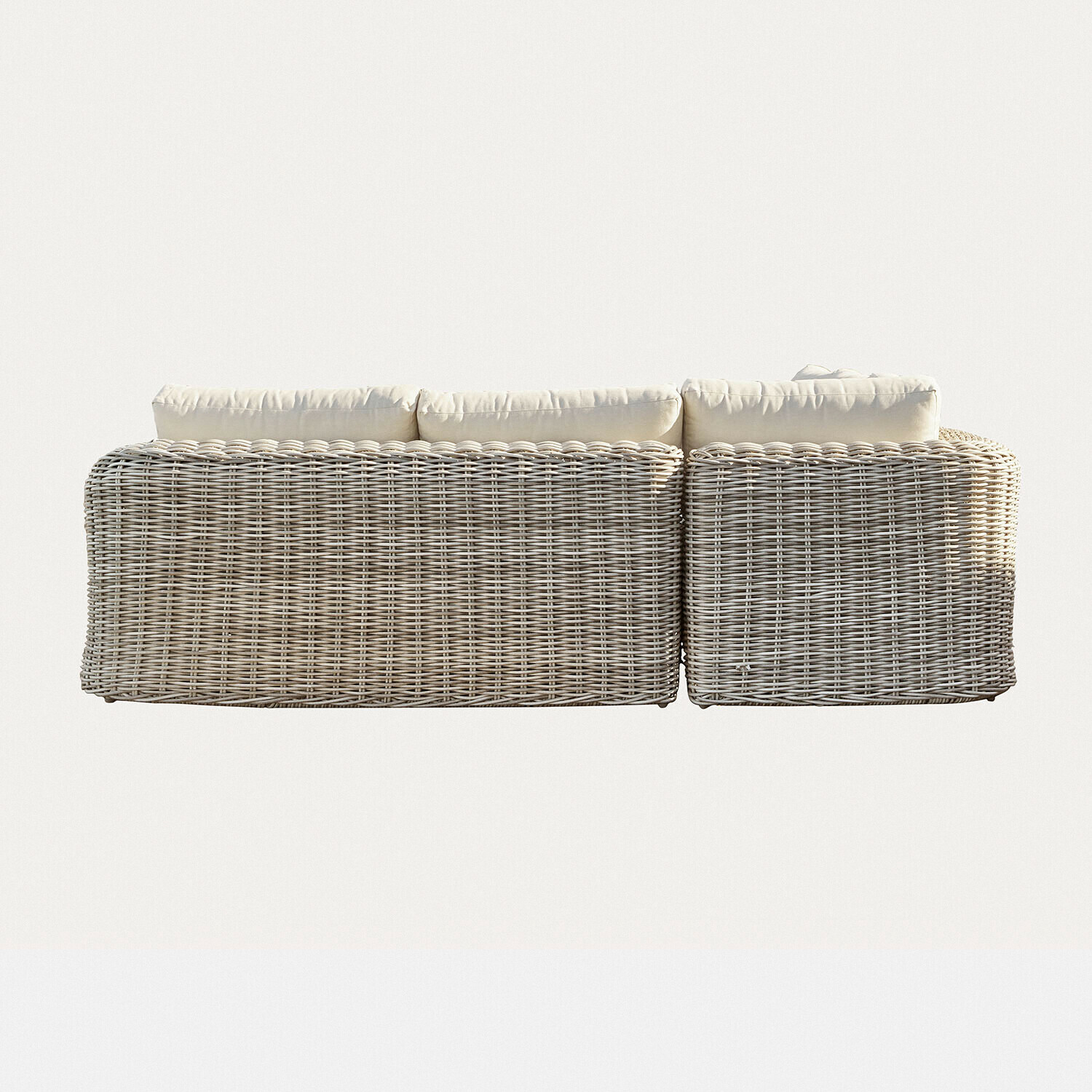 Ecksofa aus hellem Rattan mit cremefarbenen Kissen, gemütliches Möbelstück für Wohn- und Außenbereich