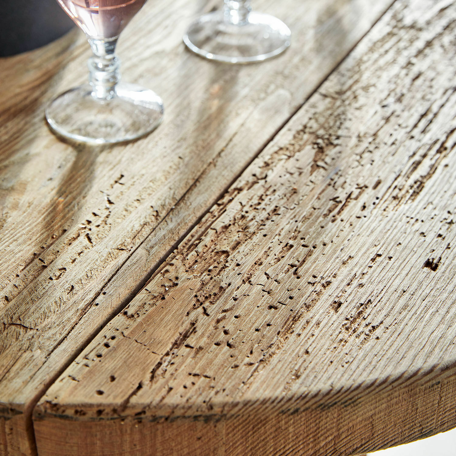 Tischplatte aus naturbelassenem, gealtertem Holz mit sichtbarer Struktur und zwei Gläsern darauf