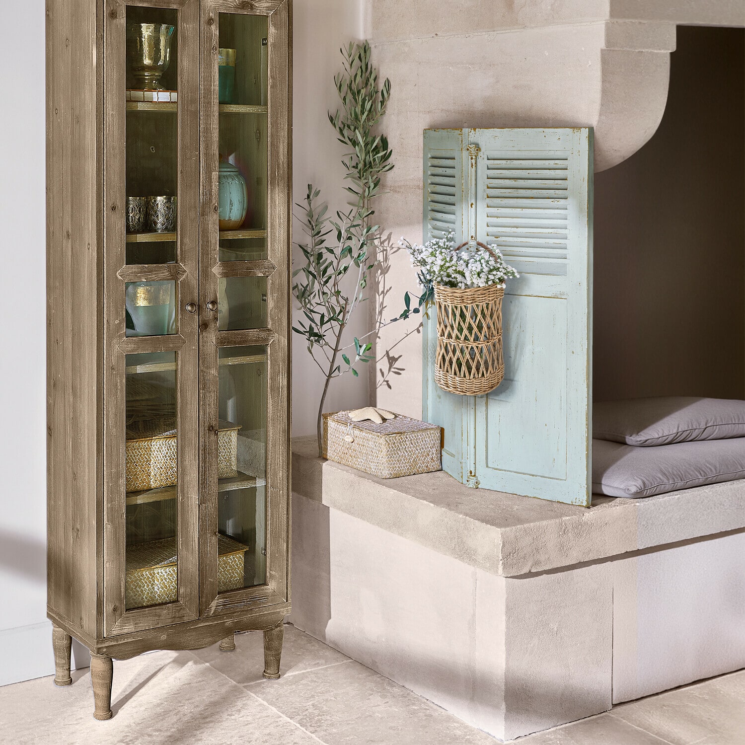 Holzvitrine mit Glastüren und Korb mit weißen Blumen als Dekoration im Raum