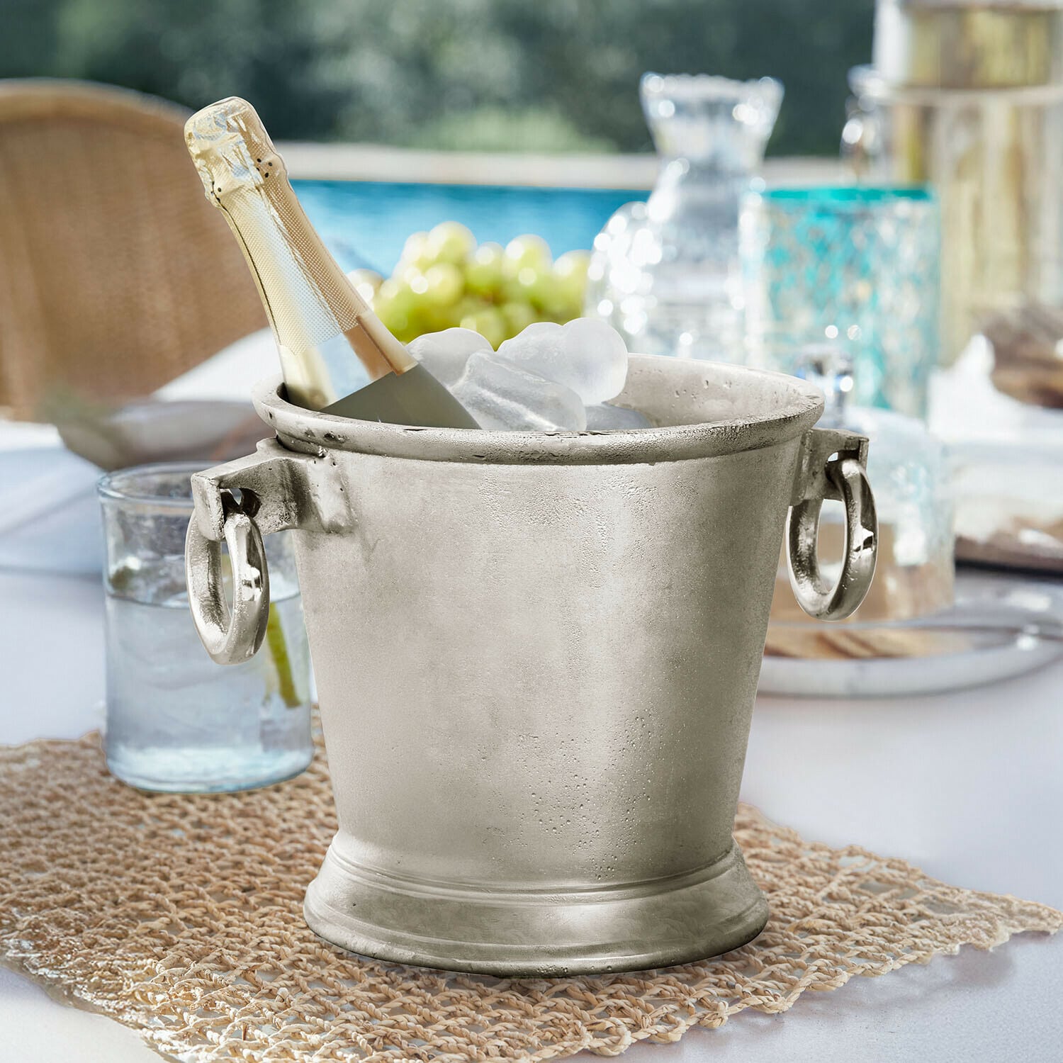 Getränkekühler Cressford Silberner Metall-Eiswürfeleimer mit Champagnerflasche und Eis auf Gartentisch