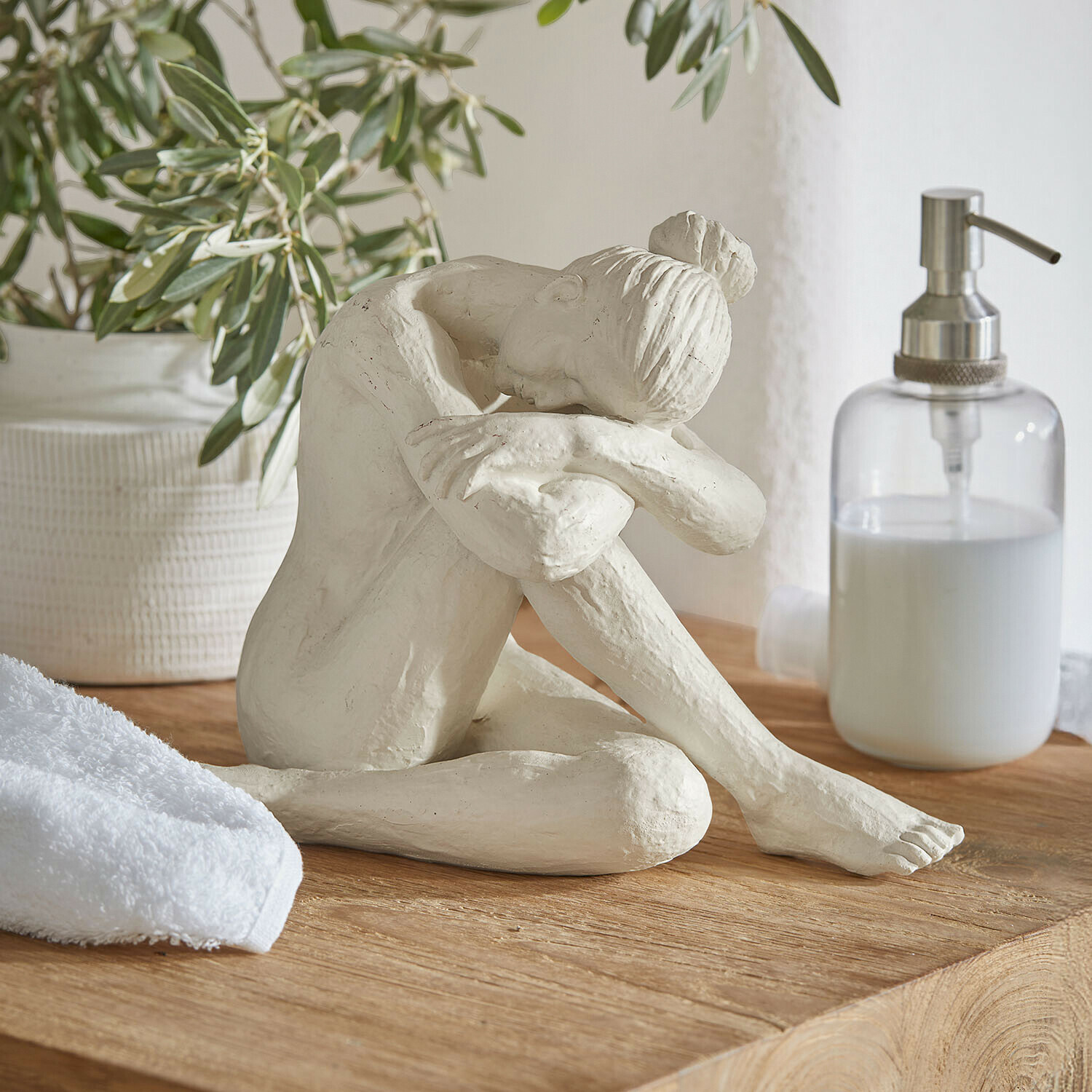 Figur Savigné Weiße Skulptur einer sitzenden Frau mit Kopf auf angewinkelten Knien auf Holzplatte im Badezimmer