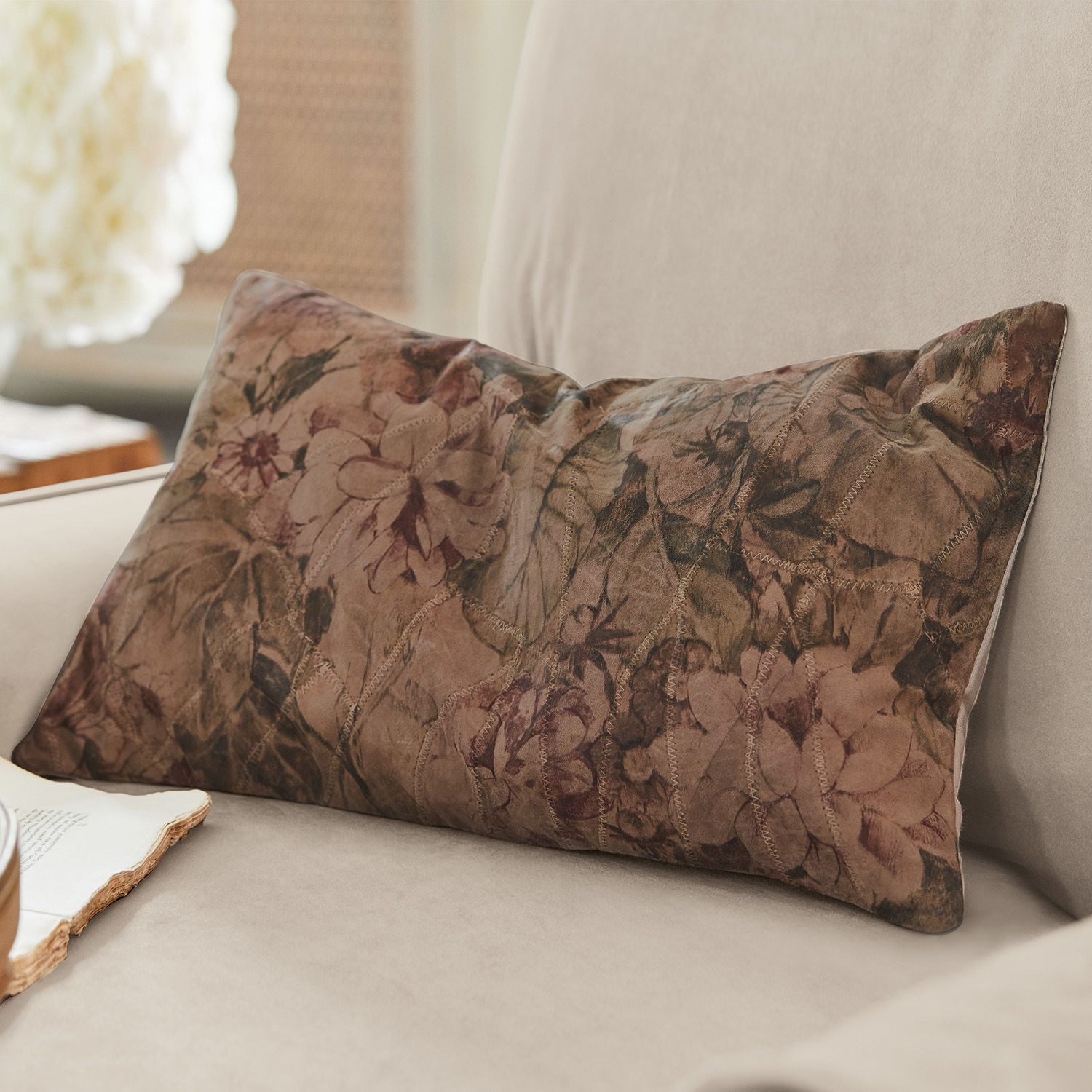 Dekoratives Kissen aus weichem Material mit braunem Blumenmuster auf Sofa