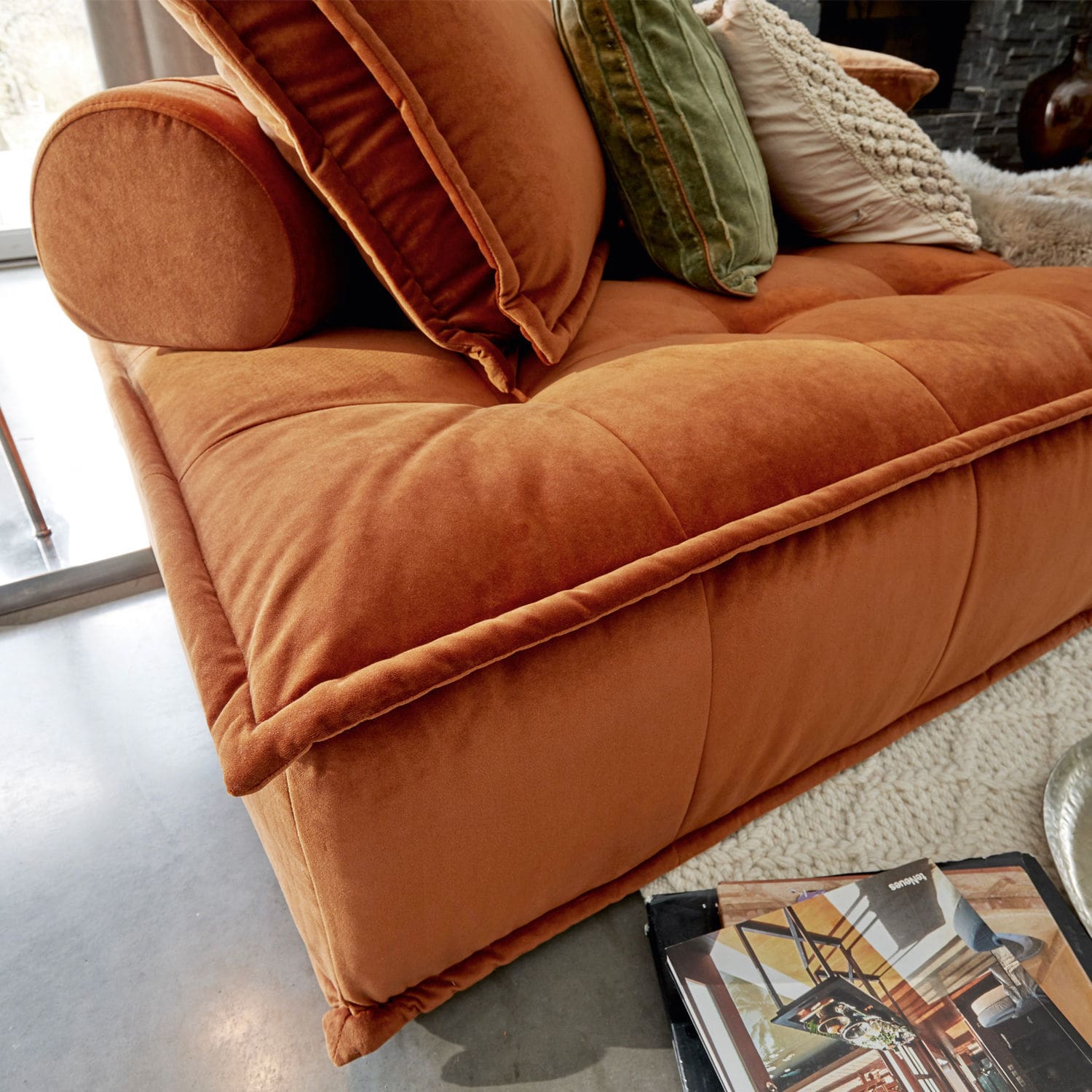 Oranger Samtsofa mit grünen und cremefarbenen Kissen in modernem Wohnzimmer