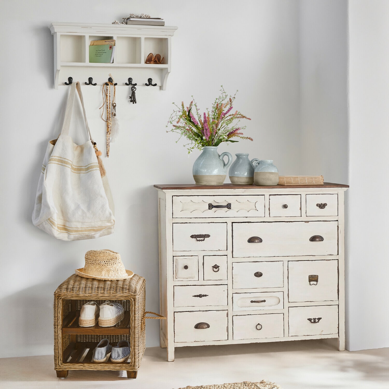 Weiße Holzkommode mit vielen Schubladen und Keramikvasen mit Blumen im Vintage-Stil auf der Ablage