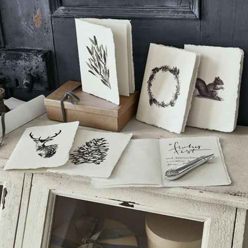 Set handgeschöpfter Karten mit Naturmotiven in Schwarz-Weiß auf hellem Papier, dekorativ auf Tisch