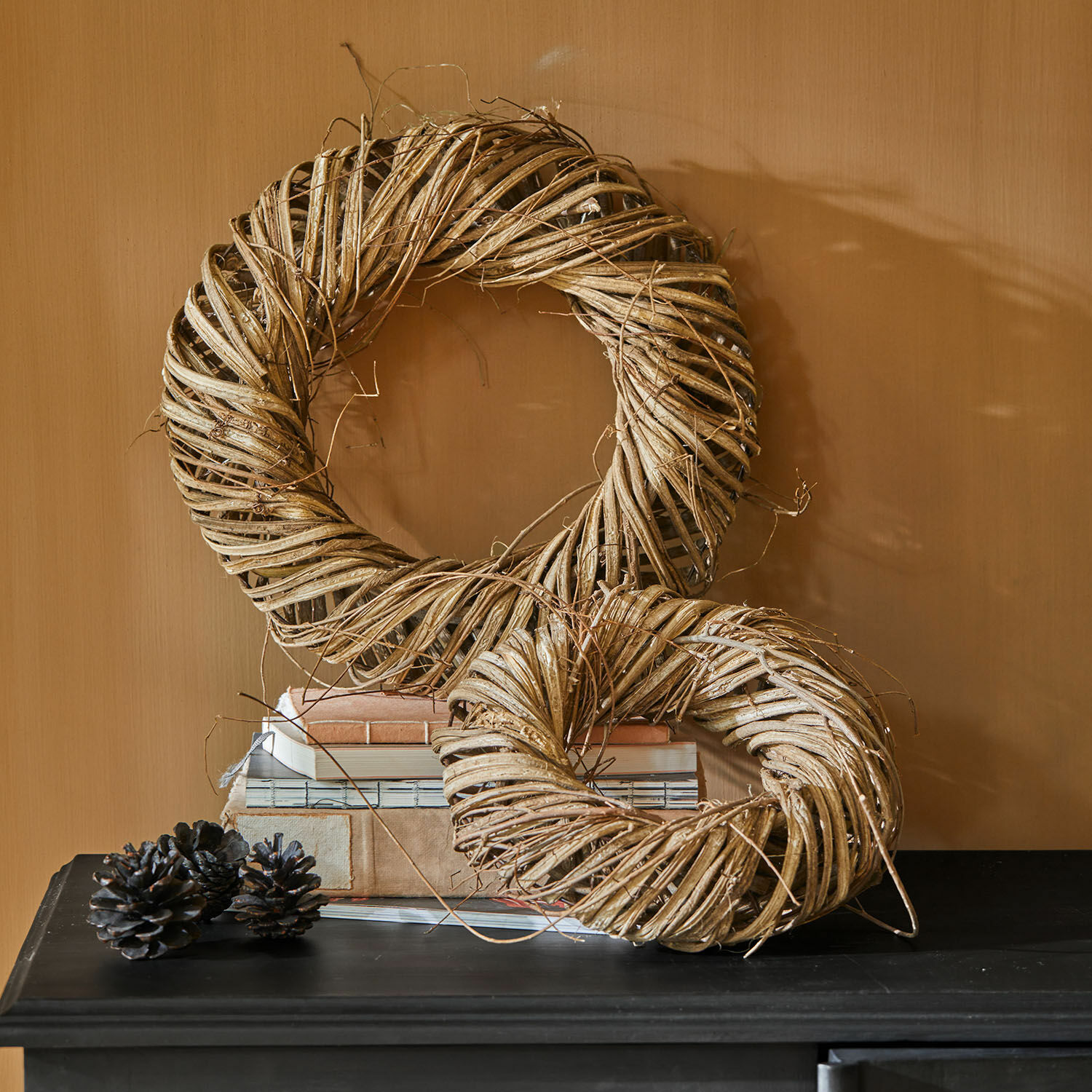 Kranz 2er Set Lunéor Dekorative Kränze aus natürlichem beige Weidenmaterial auf schwarzem Tisch mit Büchern