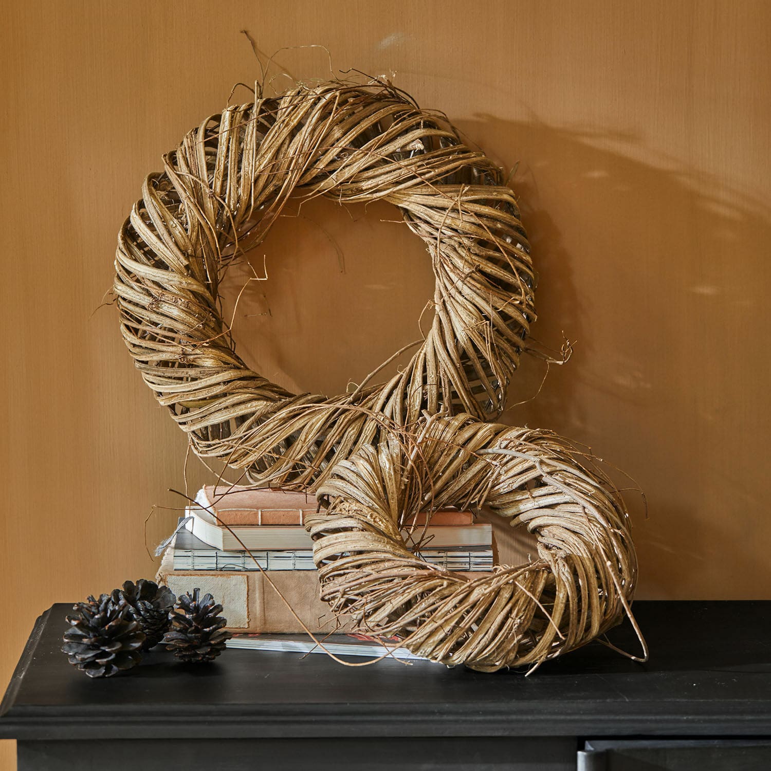 Kranz 2er Set Lunéor Dekorative Kränze aus natürlichem beige Weidenmaterial auf schwarzem Tisch mit Büchern