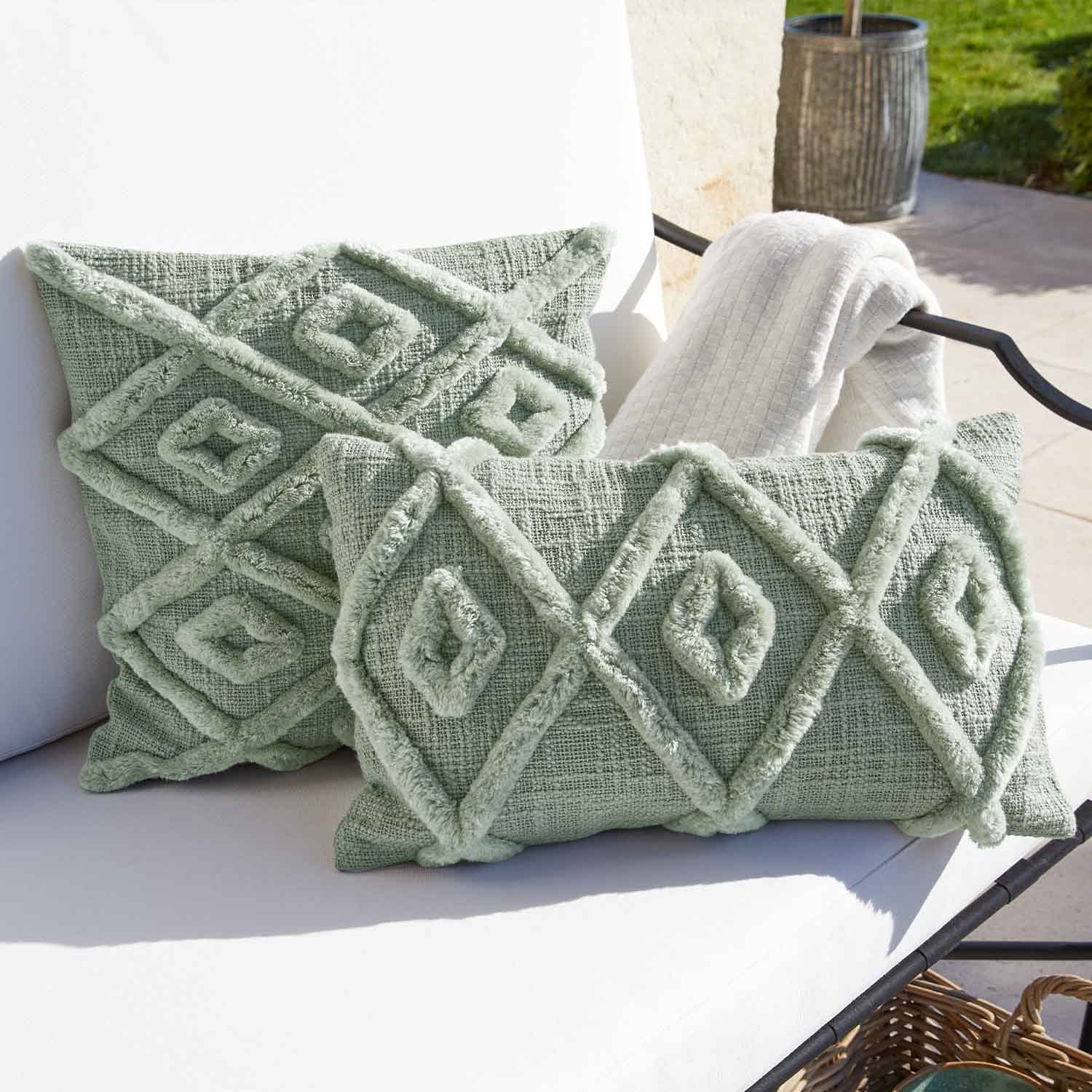 Weiches grünes Dekokissen mit geometrischem Muster auf weißem Gartenstuhl