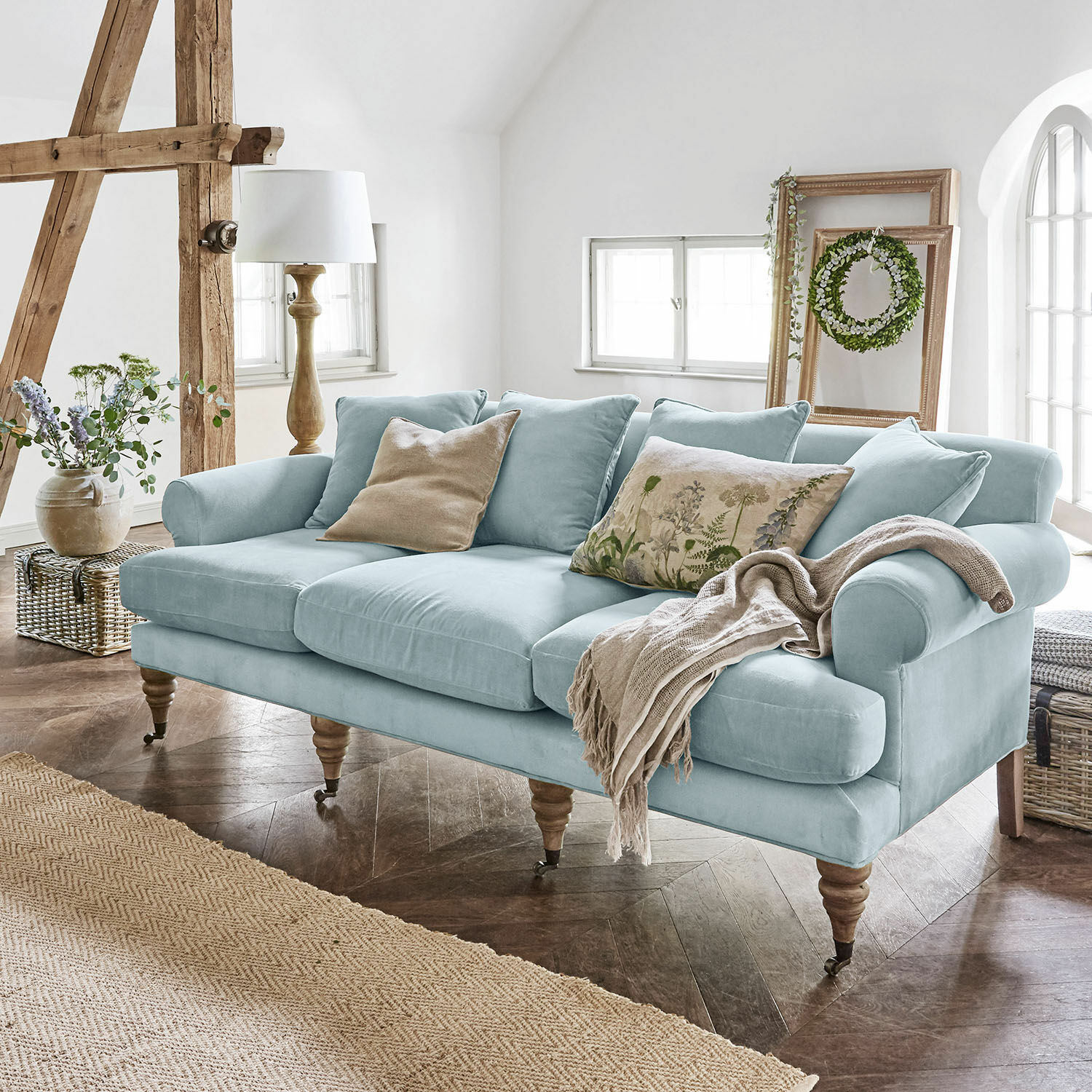 Sofa Kazimir Hellblaues Sofa aus Stoff mit Kissen und Decke in gemütlichem, hellem Wohnzimmer