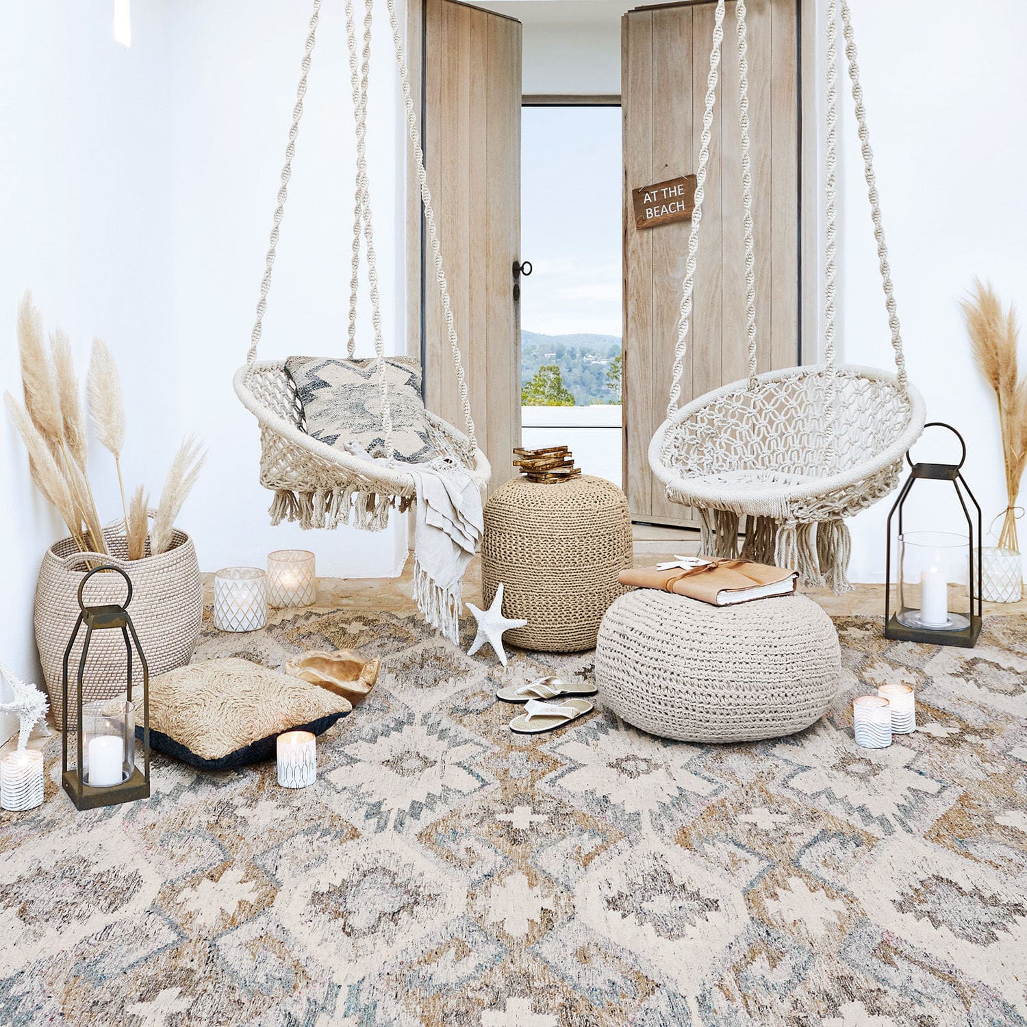 Gemütliches Wohnzimmer mit weißen Hängesesseln aus Seil und beigen Boho-Accessoires