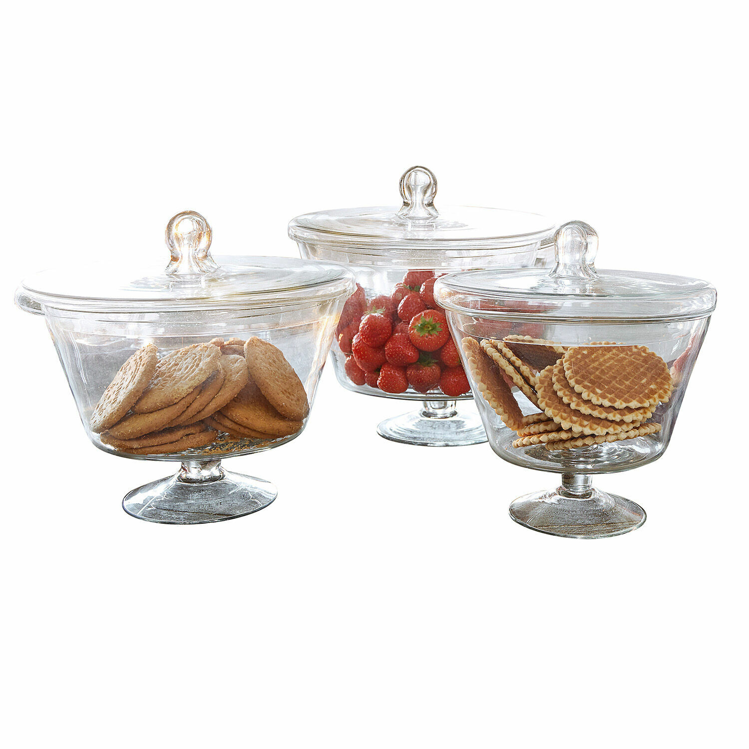 Drei transparente Glasbehälter mit Deckel auf Fuß, gefüllt mit Keksen und Erdbeeren