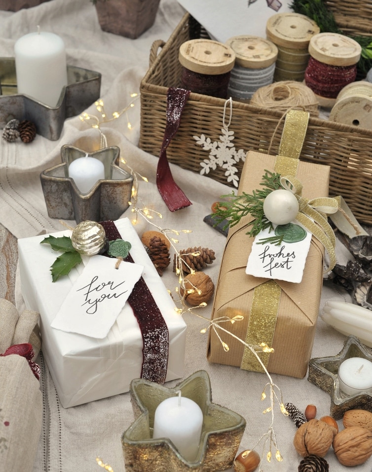 Elegante Geschenke mit Naturdeko und sternförmigen Kerzen auf Leinentischdecke festlich arrangiert