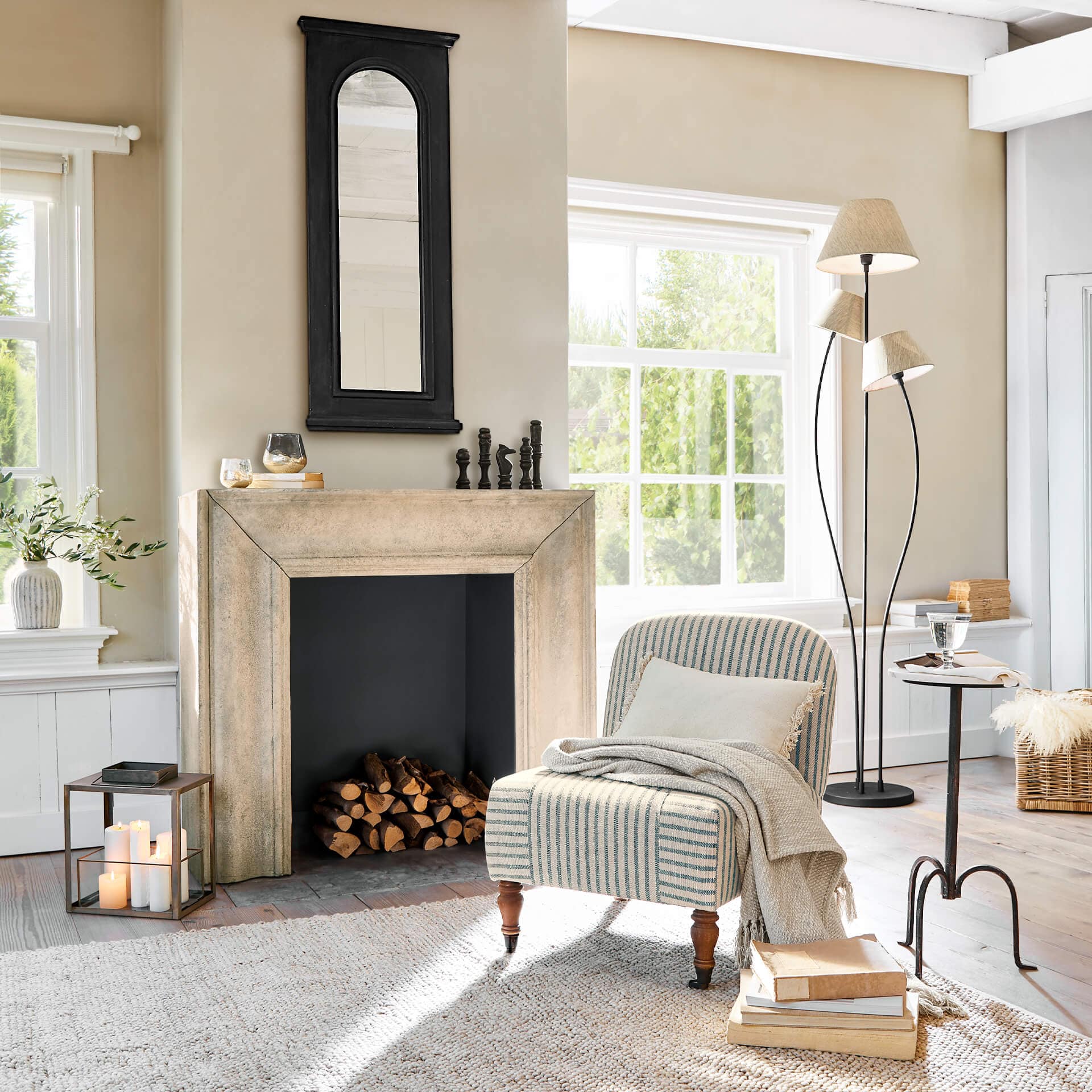 Gemütliches Wohnzimmer mit beigem Kamin, schwarzem Spiegel und gestreiftem Vintage-Sessel
