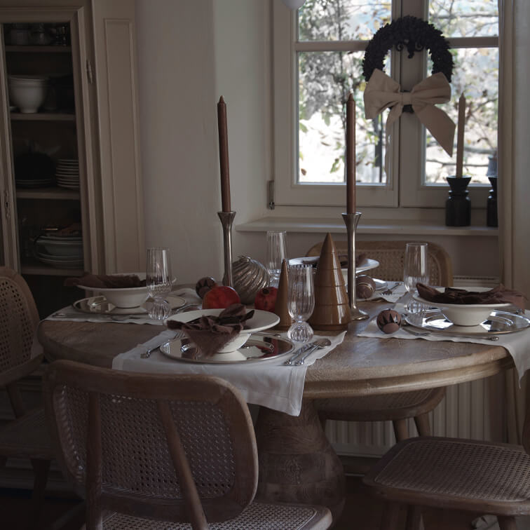 Rustikaler Holztisch mit Weihnachtsdekoration und braunen Kerzen in gemütlichem Esszimmer