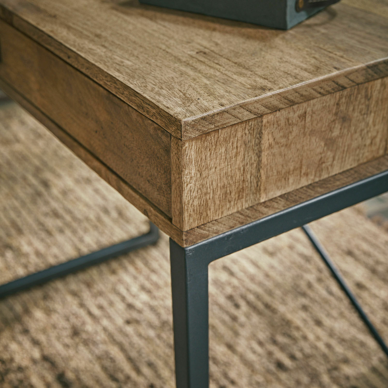Eckansicht eines Holztisches mit Metallbeinen auf Teppich, natürliche Holzfarbe