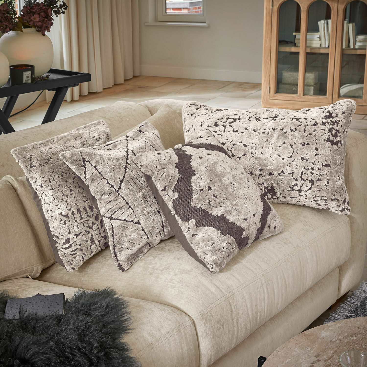 Kissenhülle 4er Set Plaisancière Vier dekorative Kissen aus weichem Material in Beige und Braun auf hellem Sofa arrangiert