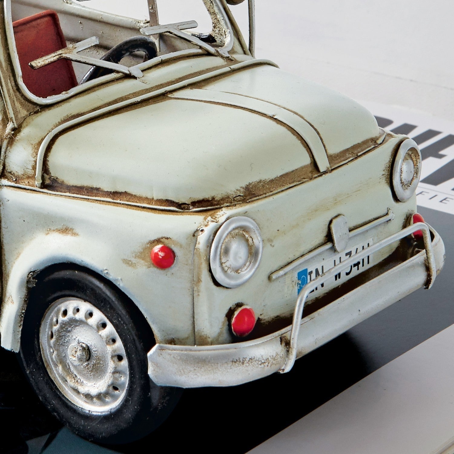 Modell eines cremeweißen Retro-Autos aus Metall mit roten Details an Rädern und Innenraum