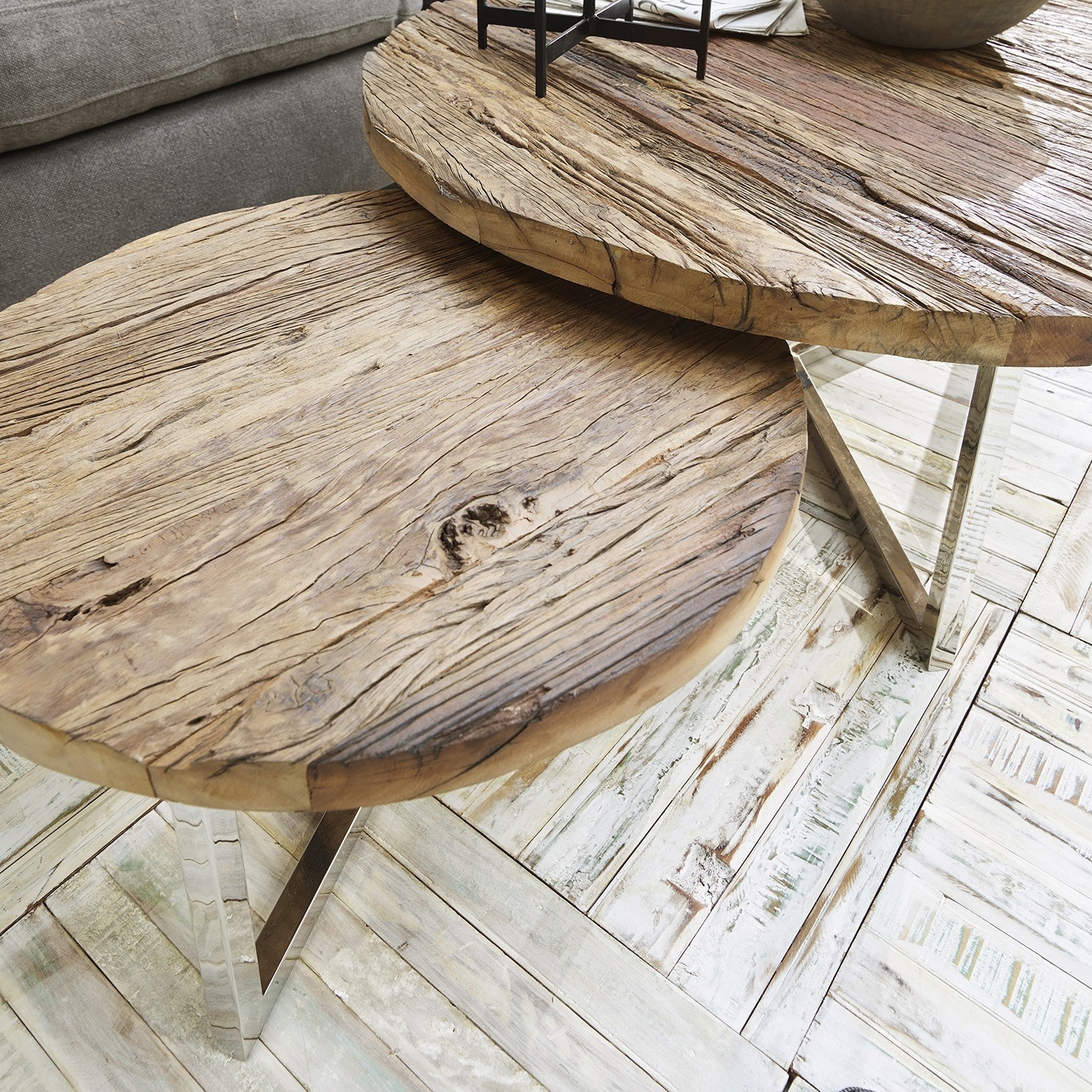 Zwei runde Couchtische aus Naturholz mit Metallbeinen auf hellem Boden