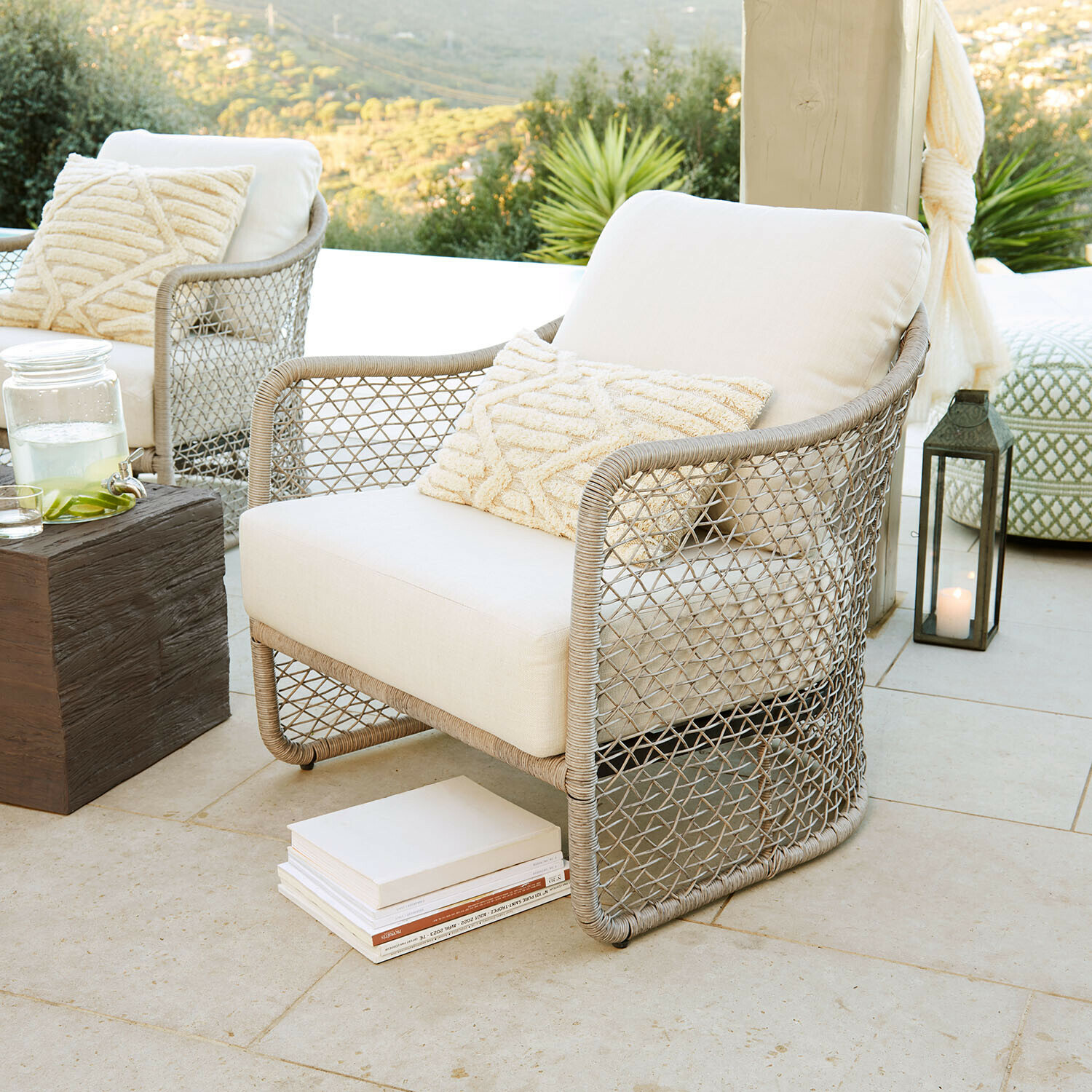 Sessel Langforda Gartenstuhl aus geflochtenem Rattan mit beigem Polster und Kissen auf Terrasse mit Naturblick