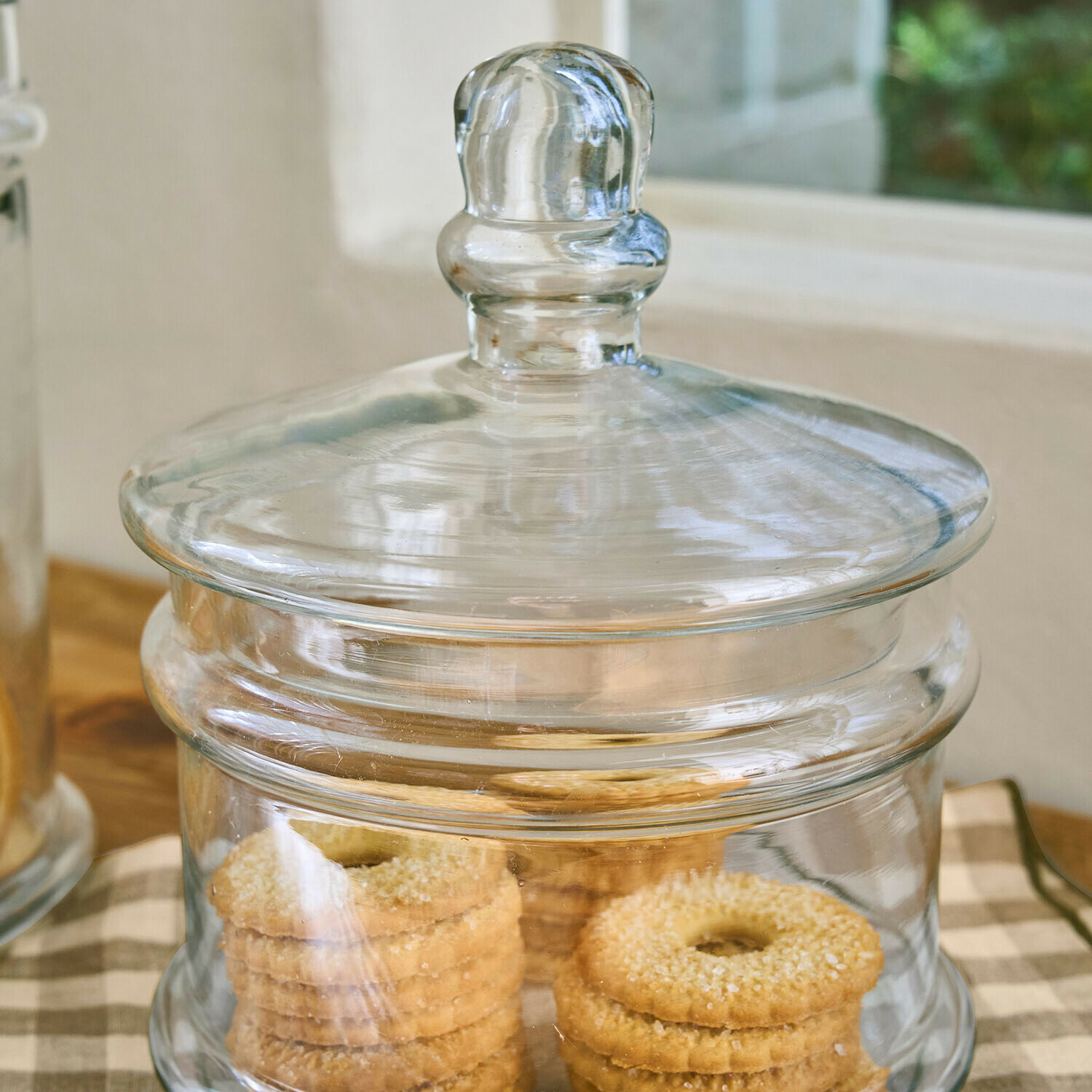 Transparenter Glasbehälter mit Deckel gefüllt mit Butterkeksen auf Küchenarbeitsplatte