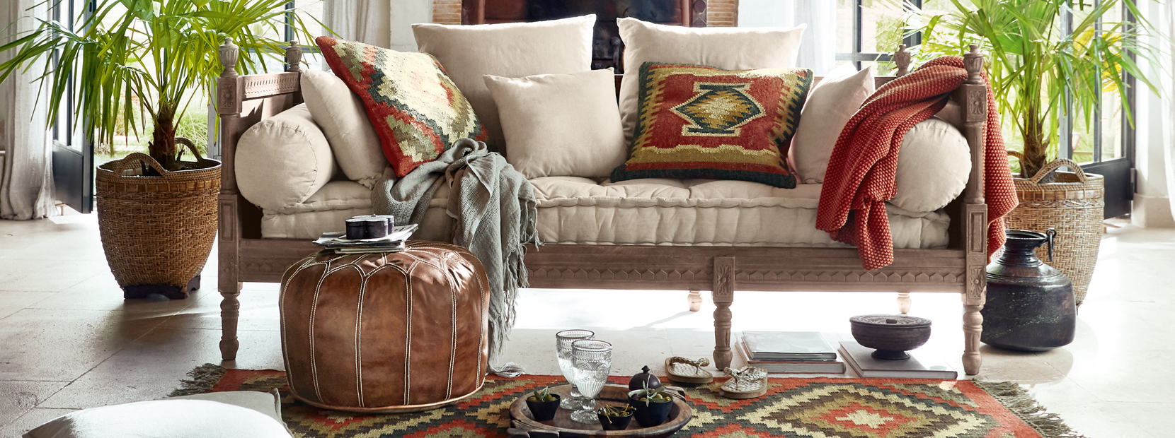 Helles Sofa mit cremefarbenen Kissen und orientalischen Mustern auf Kissen und Teppich im Wohnzimmer