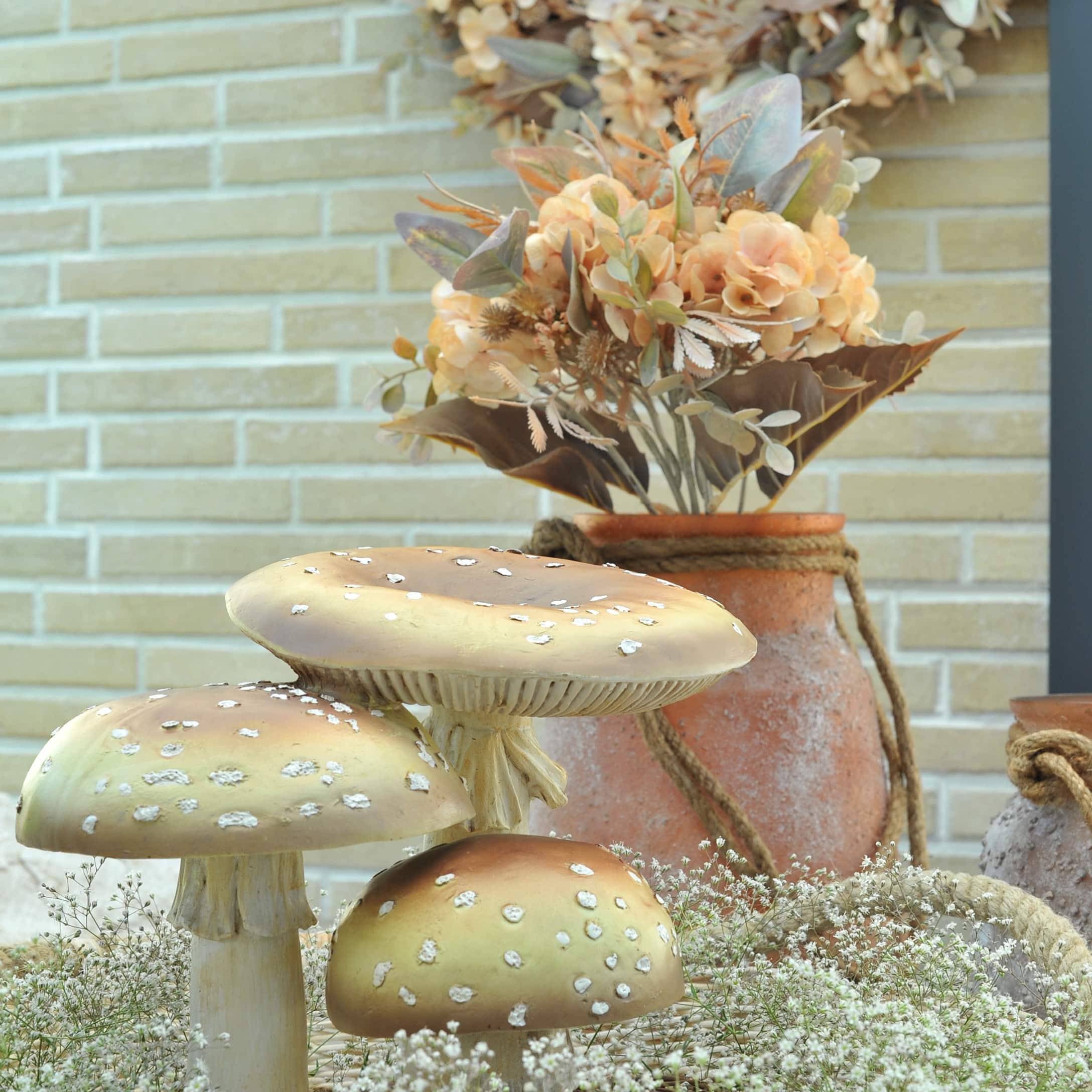 Dekorative Pilze in herbstlichen Farben mit Vase und Blumen vor Ziegelwand