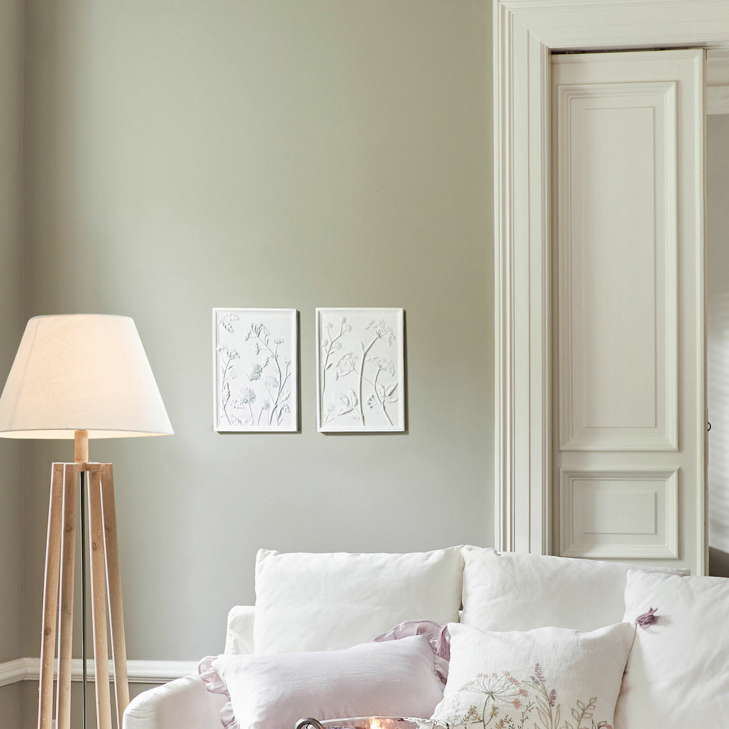 Moderne Stehlampe mit hellem Holzgestell und weißem Lampenschirm im hellen Wohnzimmer mit weißem Sofa