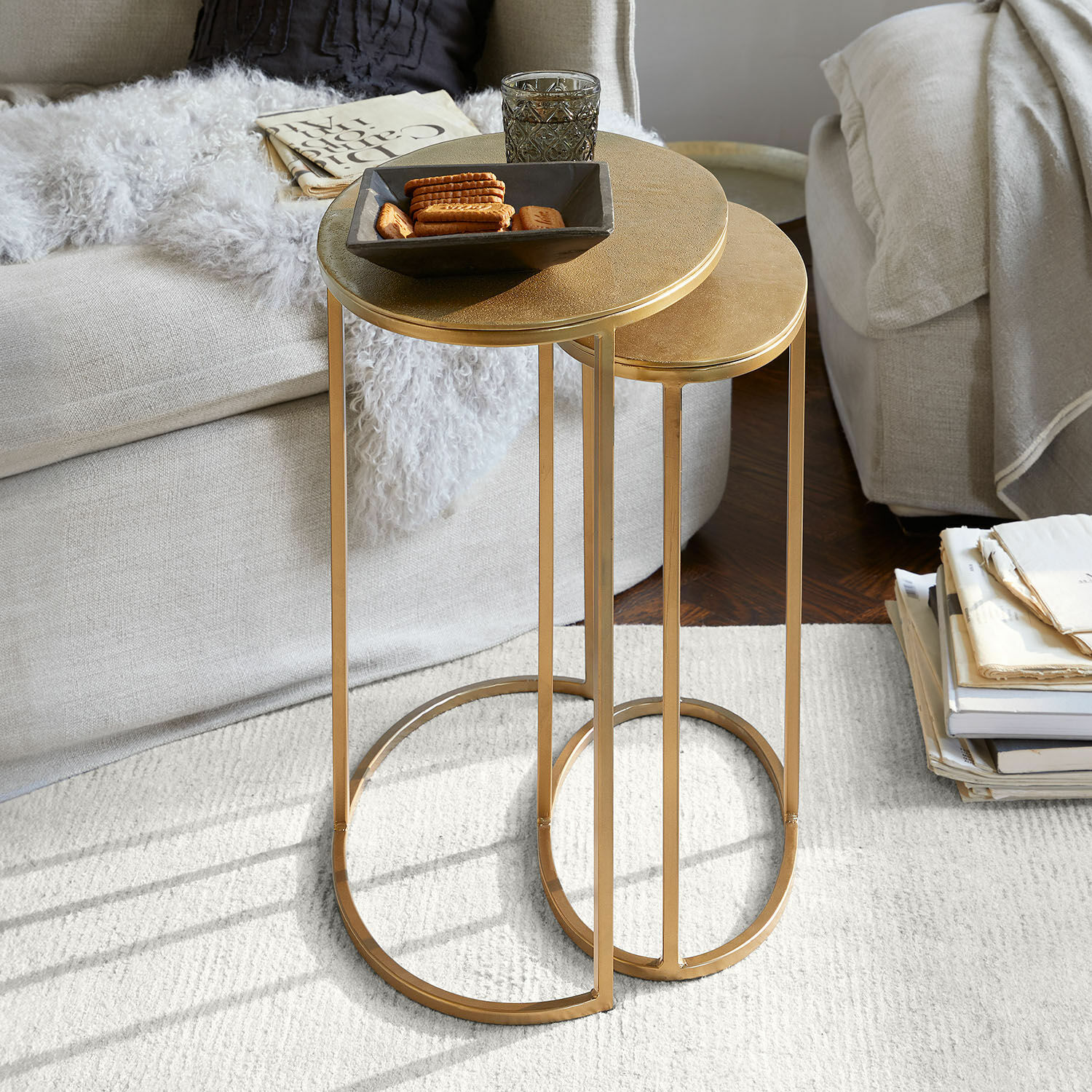 Zwei goldfarbene Metall-Beistelltische mit runden Platten in modernem Wohnzimmer auf hellem Teppich