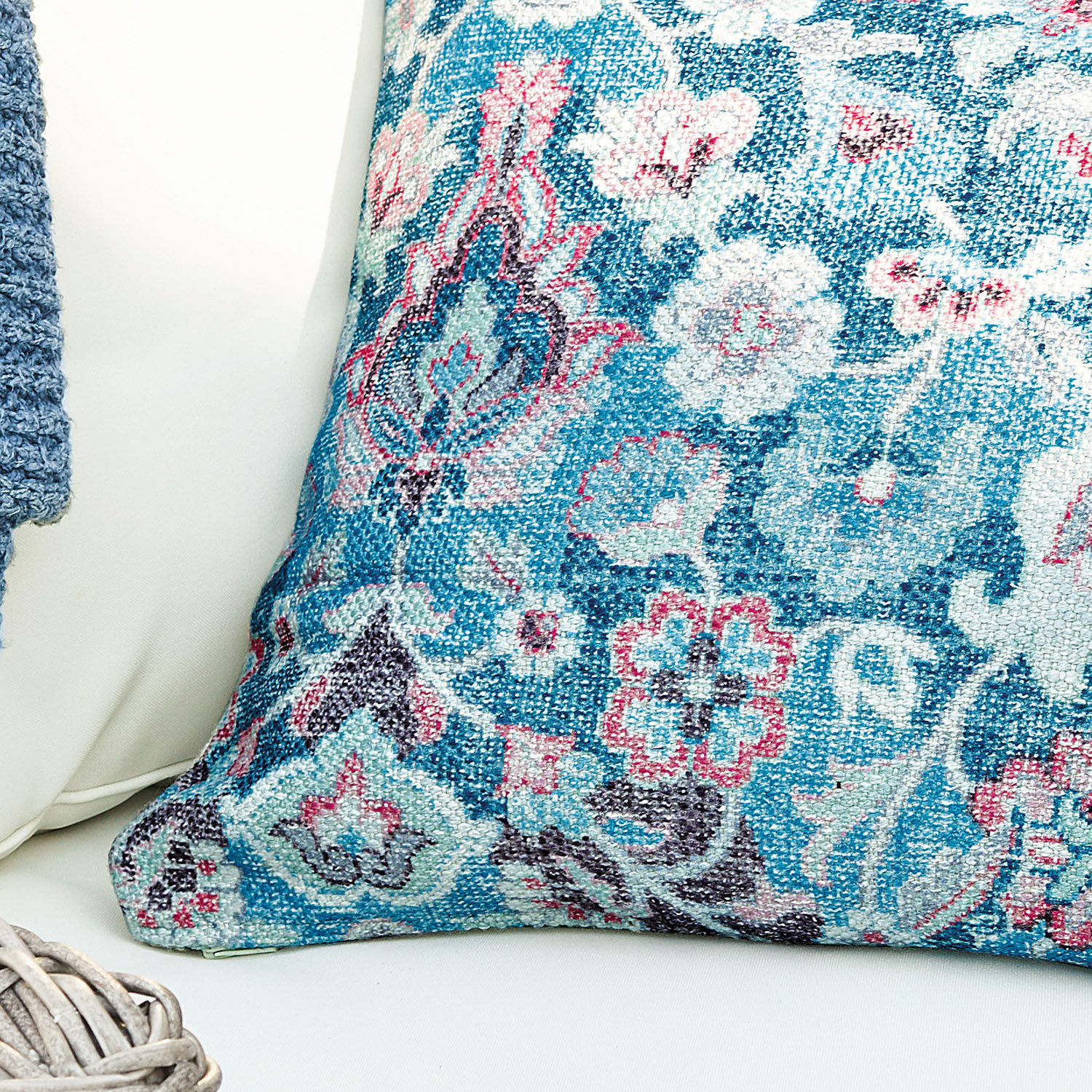 Dekoratives Kissen aus Stoff mit blau-rosa Blumenmuster auf hellem Hintergrund für Wohnzimmer