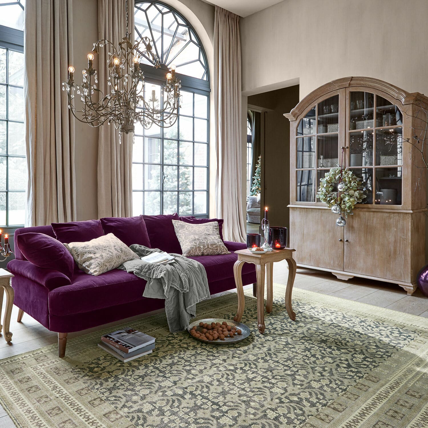 Teppich Nadimah Violette Samtsofa im Wohnzimmer mit Holzvitrine und dekorativem Vintage-Teppich
